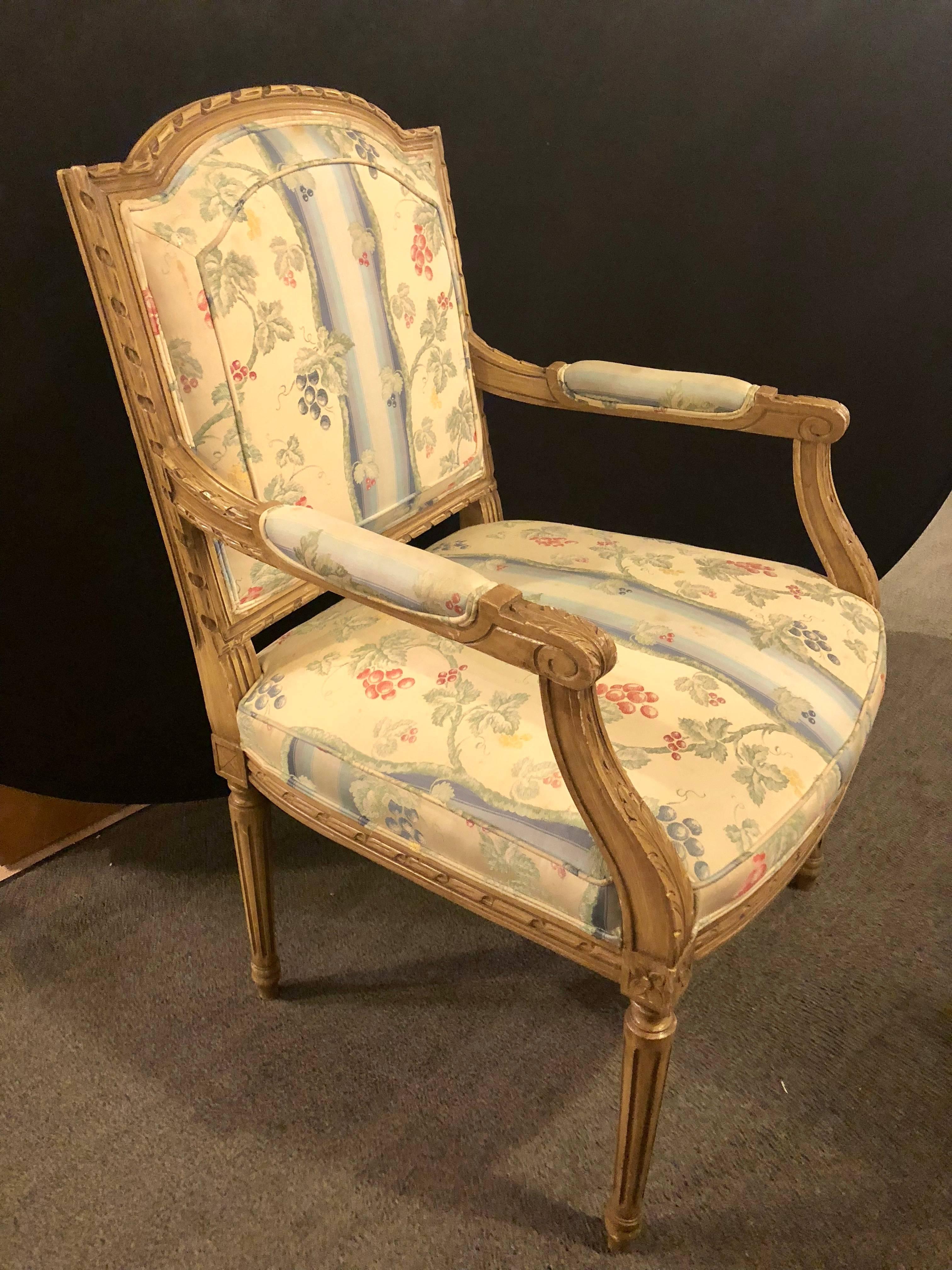 A set of ten Louis XVI style armchairs in the Maison Jansen manner. Each having a tapering leg supporting a carved apron housing a nicely stuffed upholstered seat. The pair of armchairs with nice floral wreath carvings running up the fronts. The