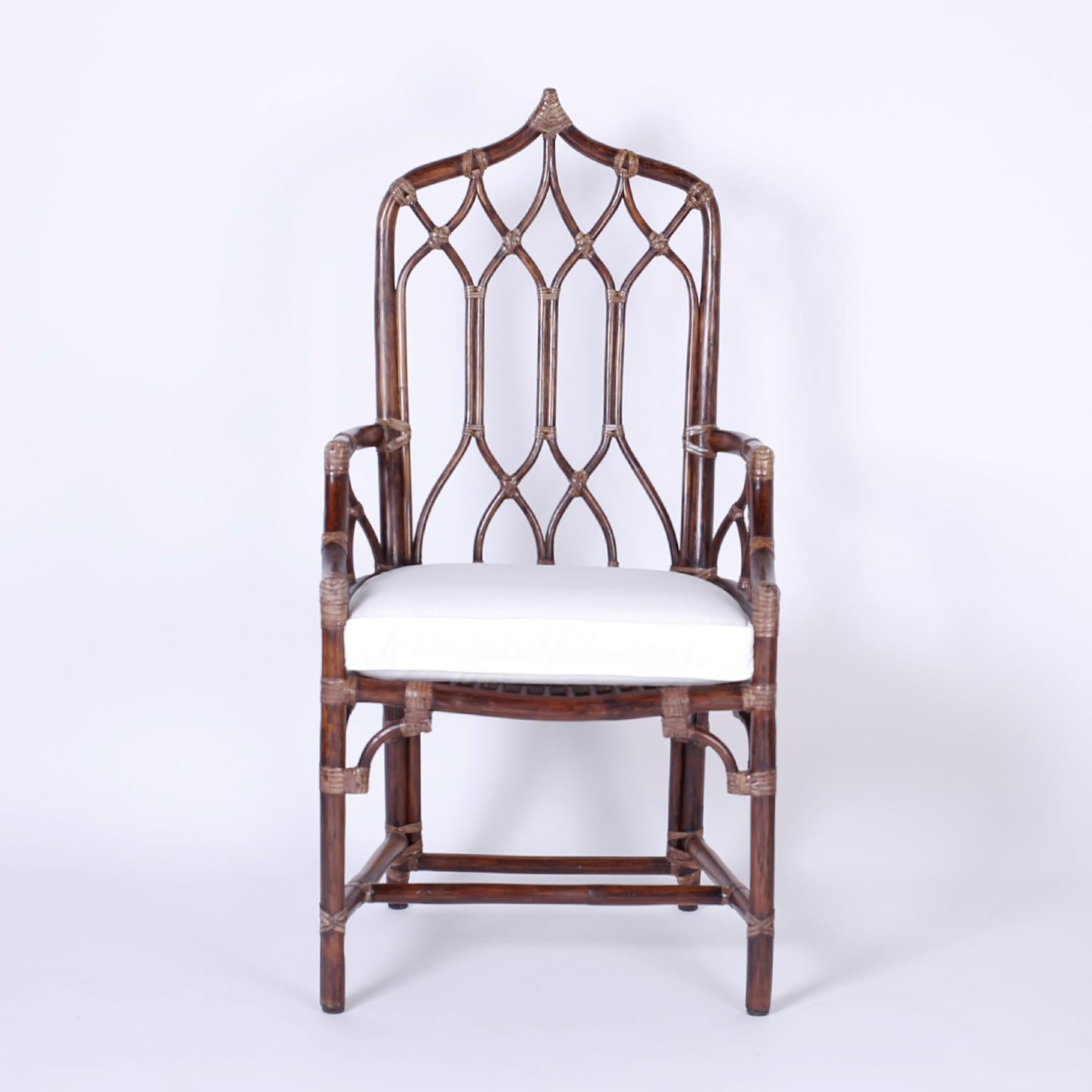 Rare set of ten dining chairs with an exotic cathedral or gothic form, graceful bentwood lines wrapped with reed at the joints, and custom cushions. Casually elegant, sturdy, comfortable, and signed McGuire on a brass plaque. 

Measures: