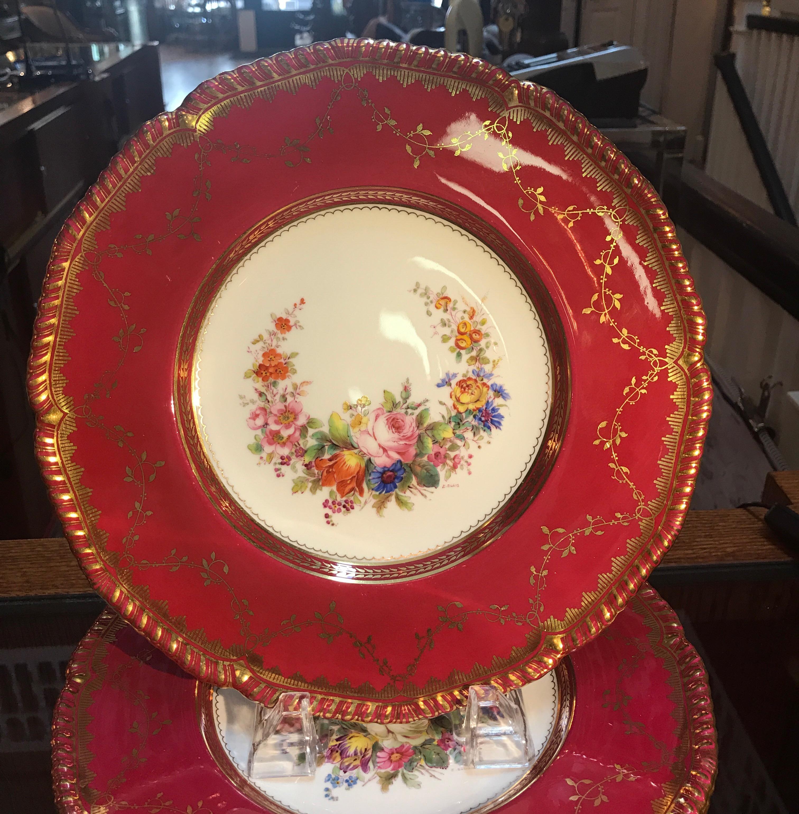 A set of ten hand-painted and gilt service dinner plates by Minton, England. The hand-painted porcelain plates with floral garlands and berry red borders with gilt overlay. Each one signed by the artist E. Ellis. Each one with the Minton mark and
