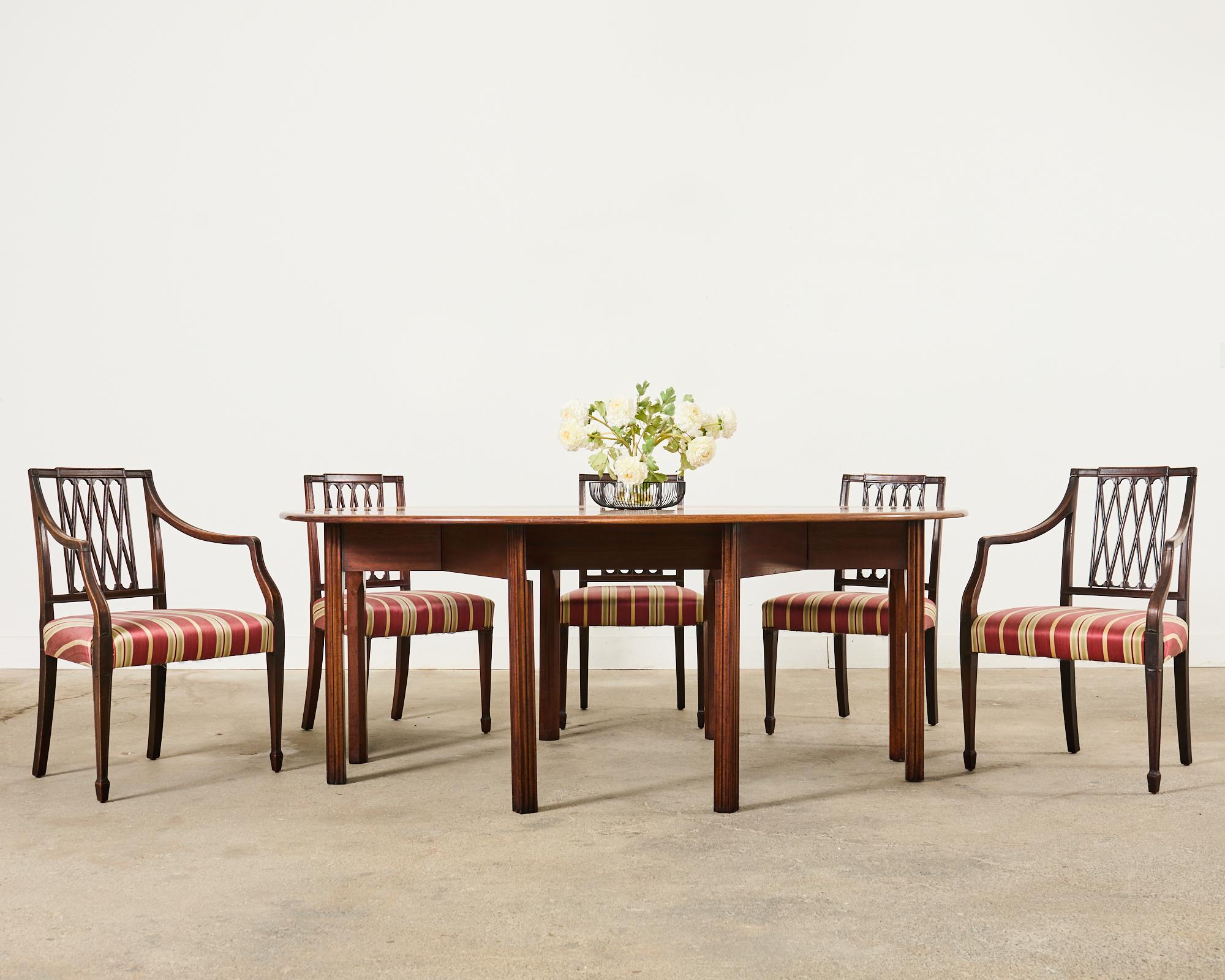 Distinctive set of ten mahogany dining chairs consisting of eight side chairs and two host armchairs measuring 24 inches wide and 21.5 inches deep. Crafted in the English Regency taste featuring a square back with a neoclassical style ribbon lattice