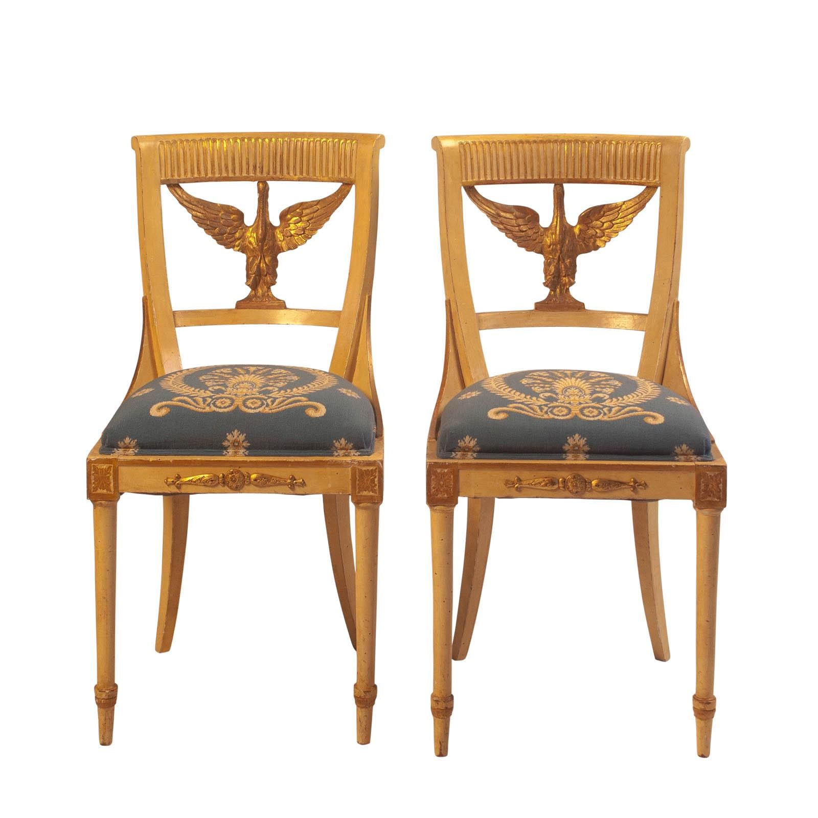 A set of ten painted and gilt Swedish dining chairs in the Empire style, circa 1900. Each chair has a giltwood swan as the back support, upholstered with needlepoint seats.