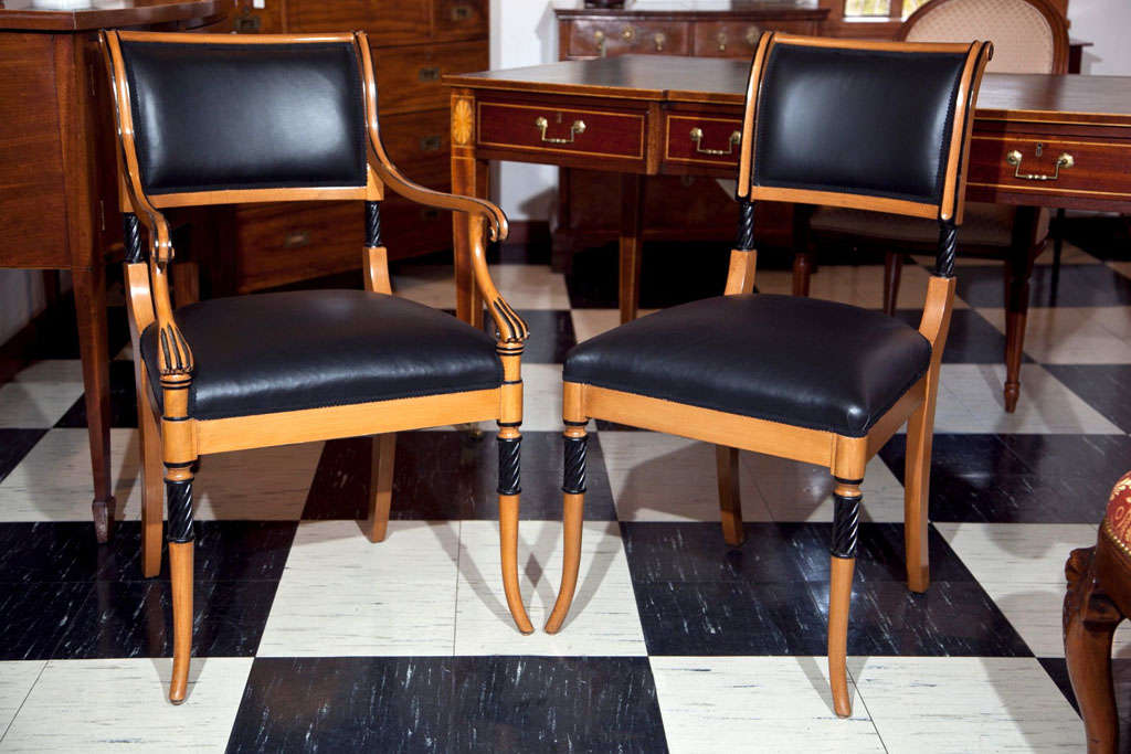 This is a set of ten (eight sides, two arms) beechwood dining chairs with ebonized accents and black leather upholstery. With an elegant and simple design, they are incredibly comfortable; the backs are double curved and nicely canted, while the