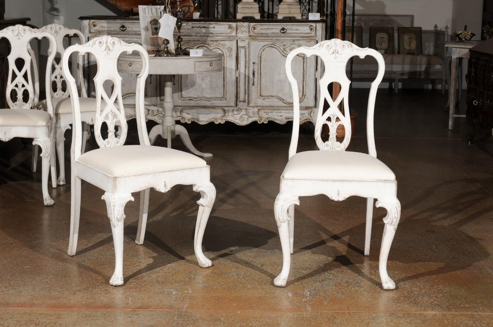 Un ensemble de dix chaises de salle à manger de style rococo scandinave en bois peint du 20e siècle, avec éclisses sculptées, pieds cabriole et tapisserie neuve. Créé en Scandinavie, cet ensemble de dix chaises de salle à manger présente un splat