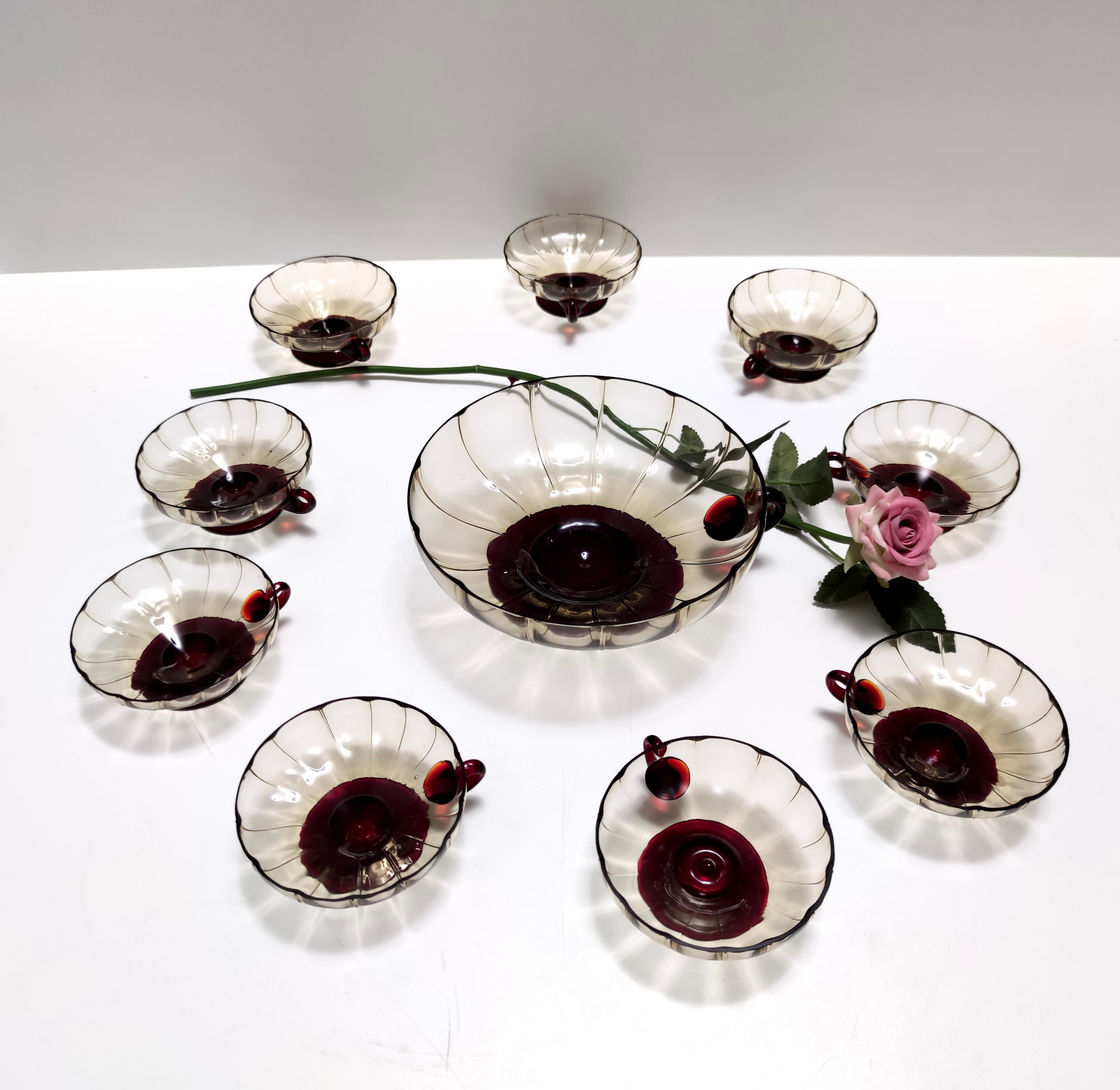 Made in Italy, 1920s - 1930s. 
This is an elegant set of serving bowls.
This set is in the style of Vittorio Zecchin for Cappellin or Venini. 
Its color is particular as its a straw-colored smoked glass with crimson details. 
This is a vintage set,