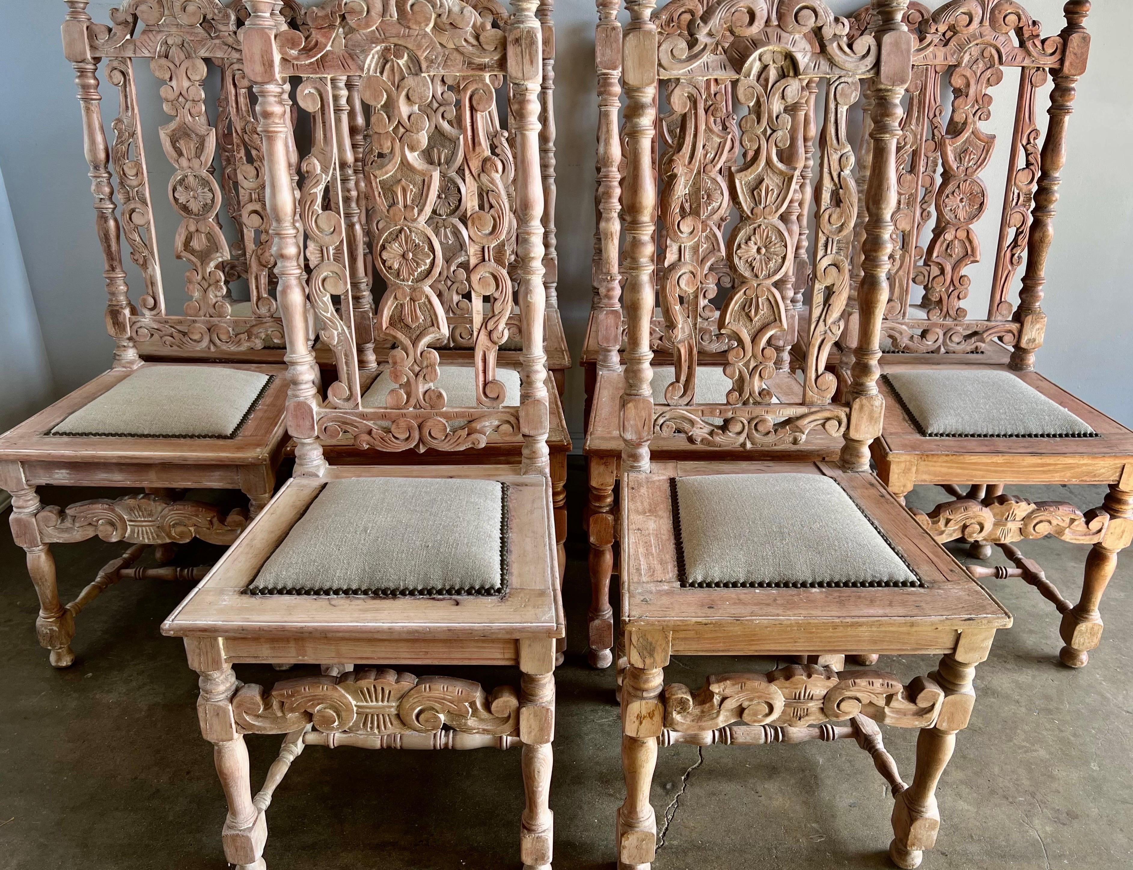 Set of ten bleached walnut Spanish Baroque style dining chairs. The chairs are intricately carved with beautiful details throughout including scrolls, acanthus leaves and flowers throughout the chairs. The dining chairs are newly upholstered in