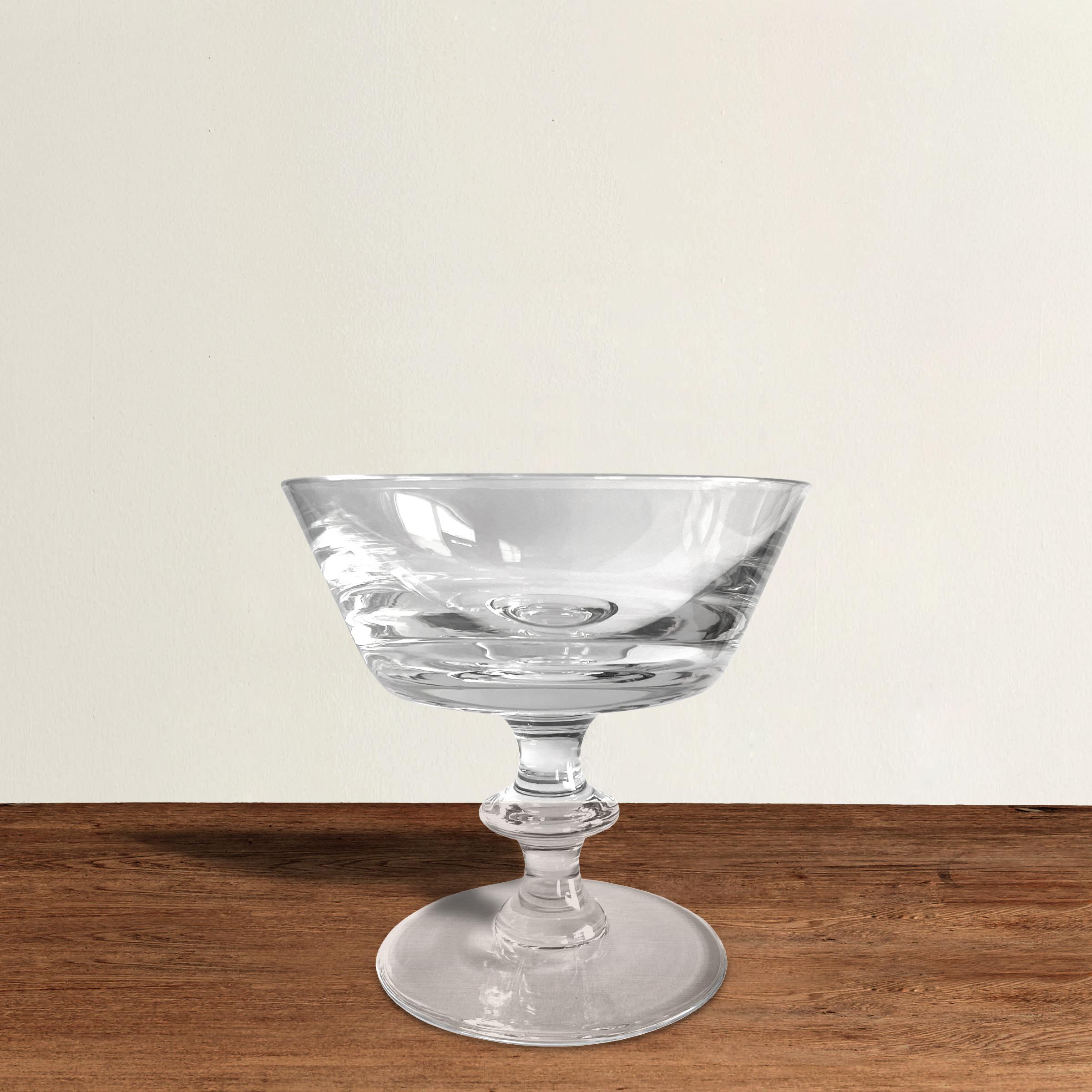 A covetable set of ten blown crystal champagne coupes by famed Belgian crystal company, Val Saint Lambert, in the State Plain pattern, each with a simple bowl with straight sides and a stem with a single knot and resting on a wide flat foot. This