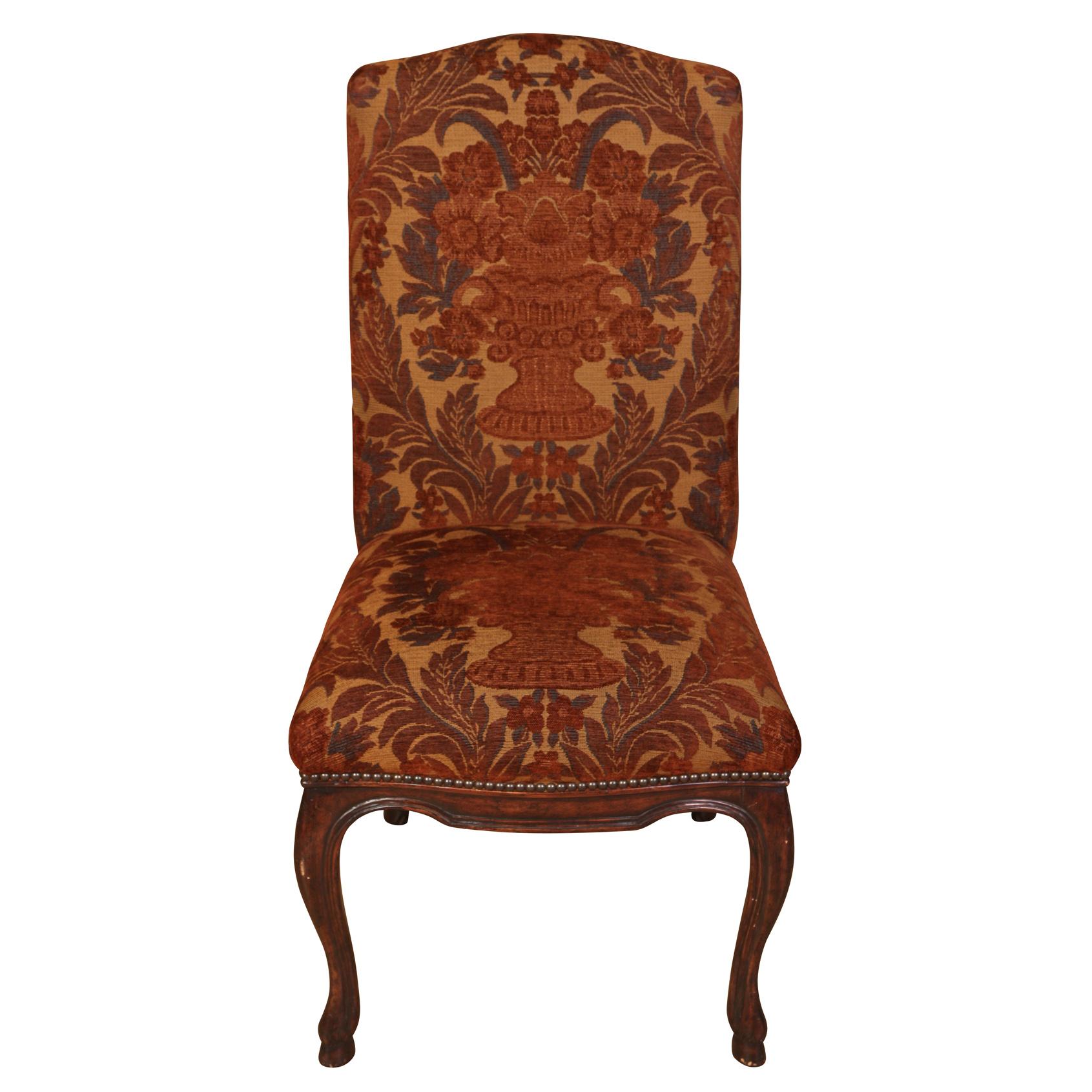 A vintage set of dining chairs by Michael Taylor with cranberry and gold brocade fabric of urns with flowers and leaves, cabriole legs and nail head trim to shaped seat backs. Armchairs measure 23.5