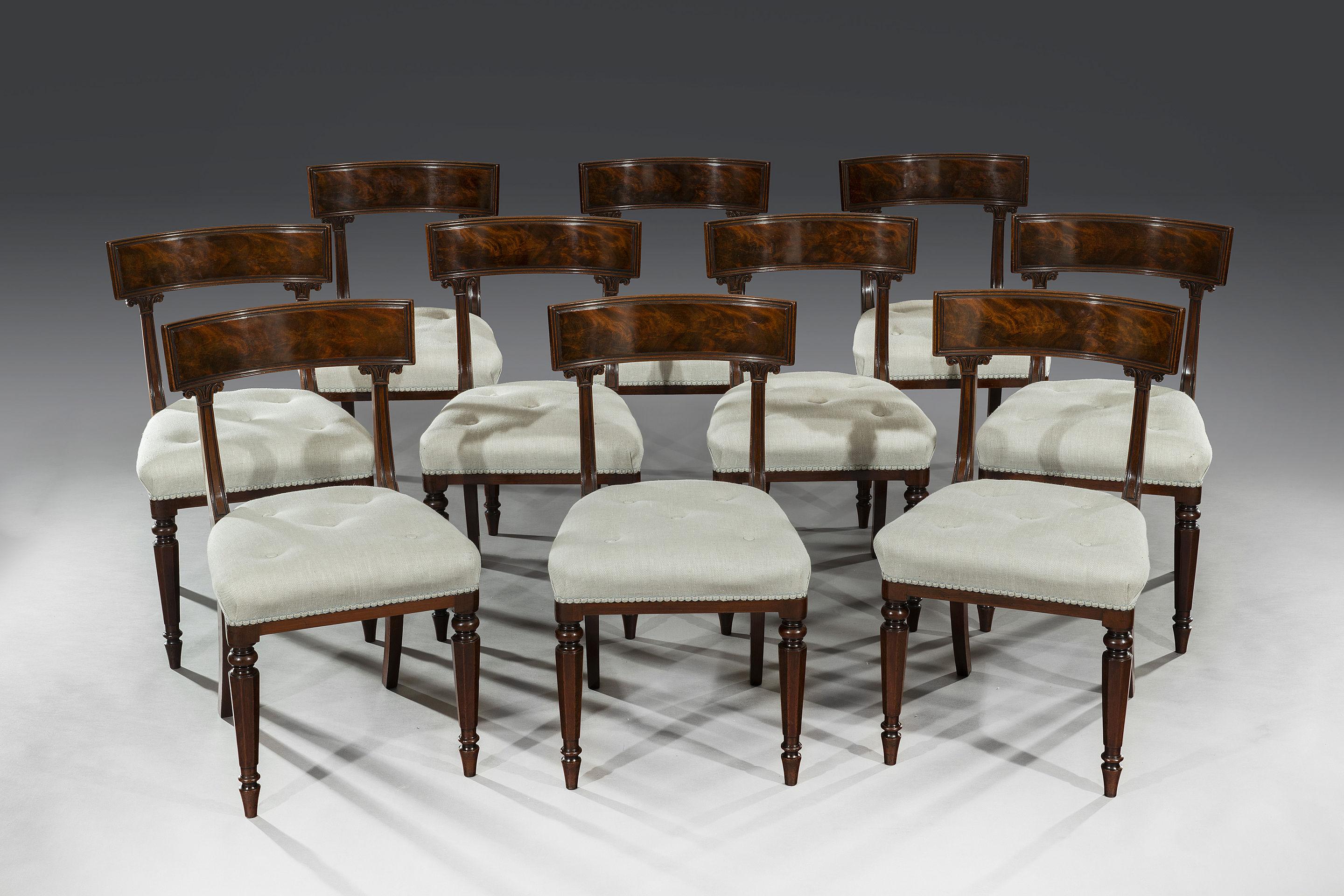 The concave back rails with flamed mahogany veneers and open shaped backs and carved splats sit above stuff-over seats. The recently re-covered upholstered seats above turned and faceted tapered legs stand on toupe feet.