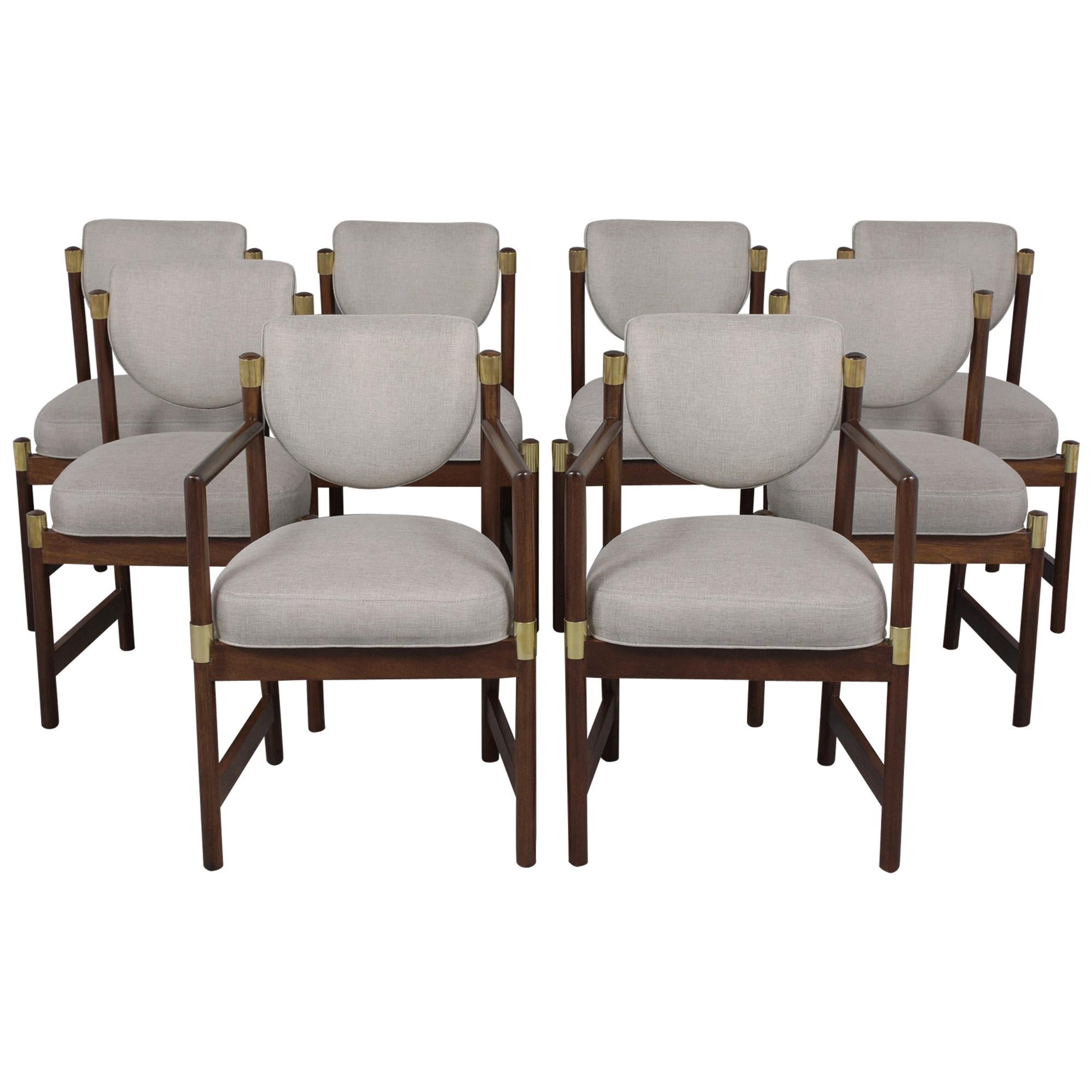 A set of eight Mid-Century Modern dining chairs in a manner of T.H. Robsjohn Gibbings in excellent condition that has been hand-crafted out of walnut and restored by our team of craftsmen This set comes with two armchairs and six side chairs that