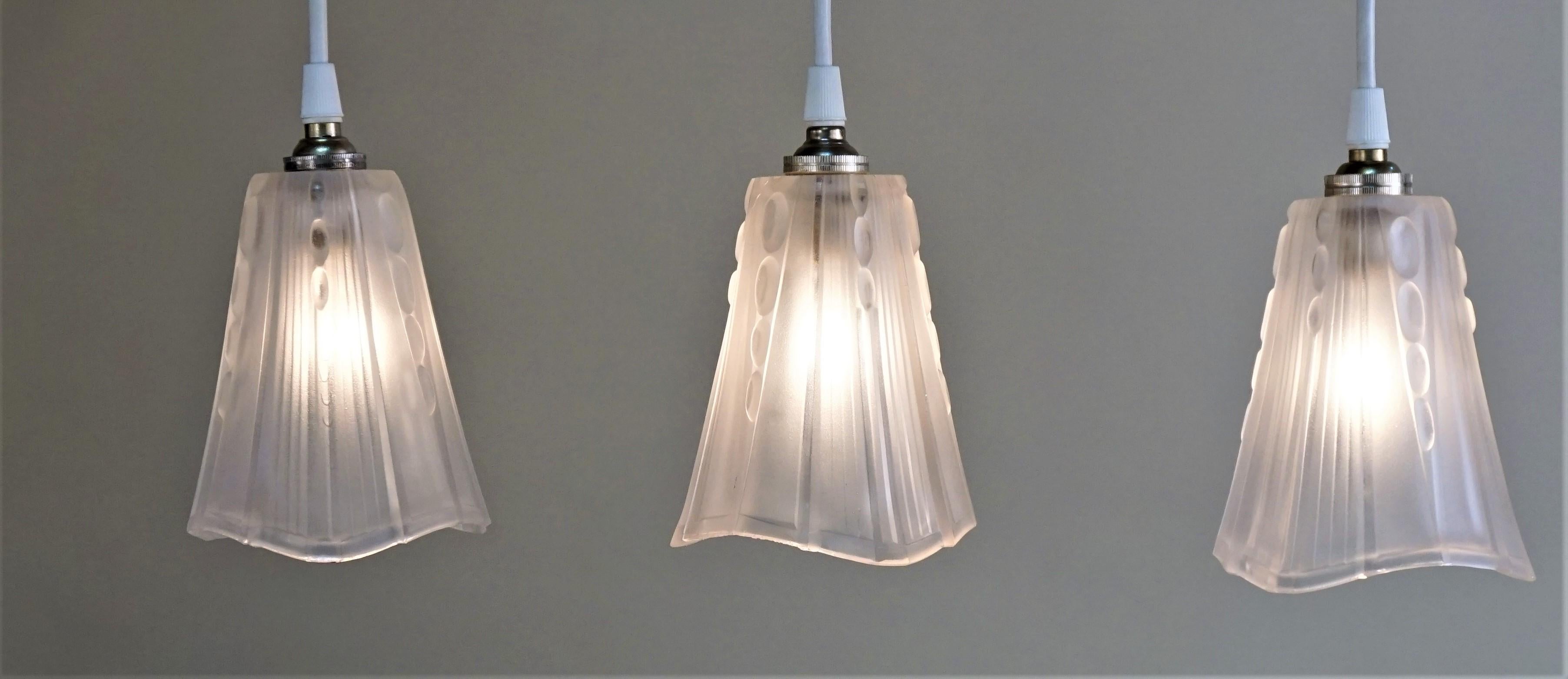 Set of three 1930s Art Deco glass shades by E.J.G. that have been modified with new white cord and nickel canopy as pendant lights.

Price is for set of 3.