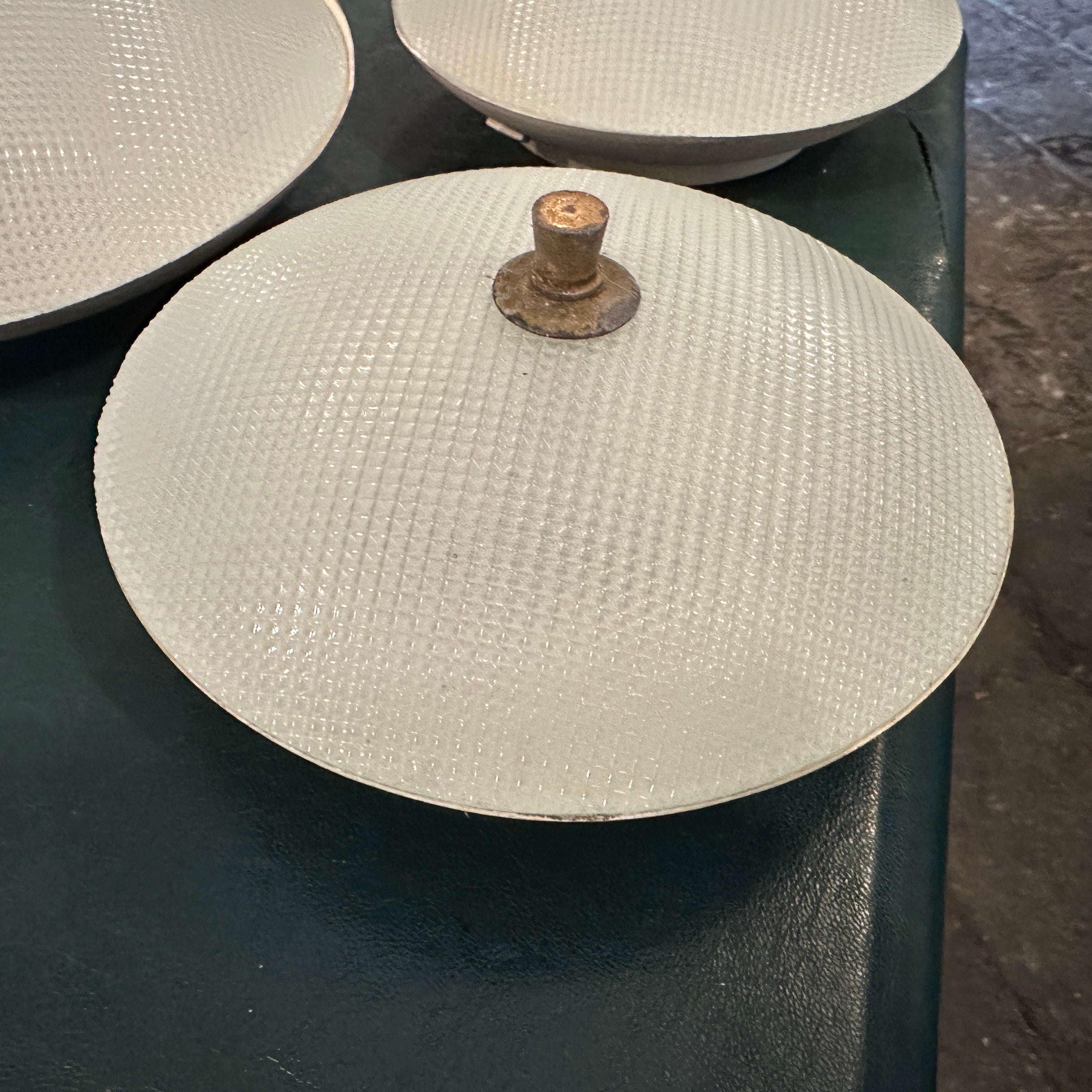Set di tre bellissime plafoniere a disco, produzione italiana originale degli anni '50 alla maniera dello Stilnovo Base di fissaggio a parete in metallo smaltato avorio, paralume in vetro stampato. Chiusura con bottone centrale a vite in