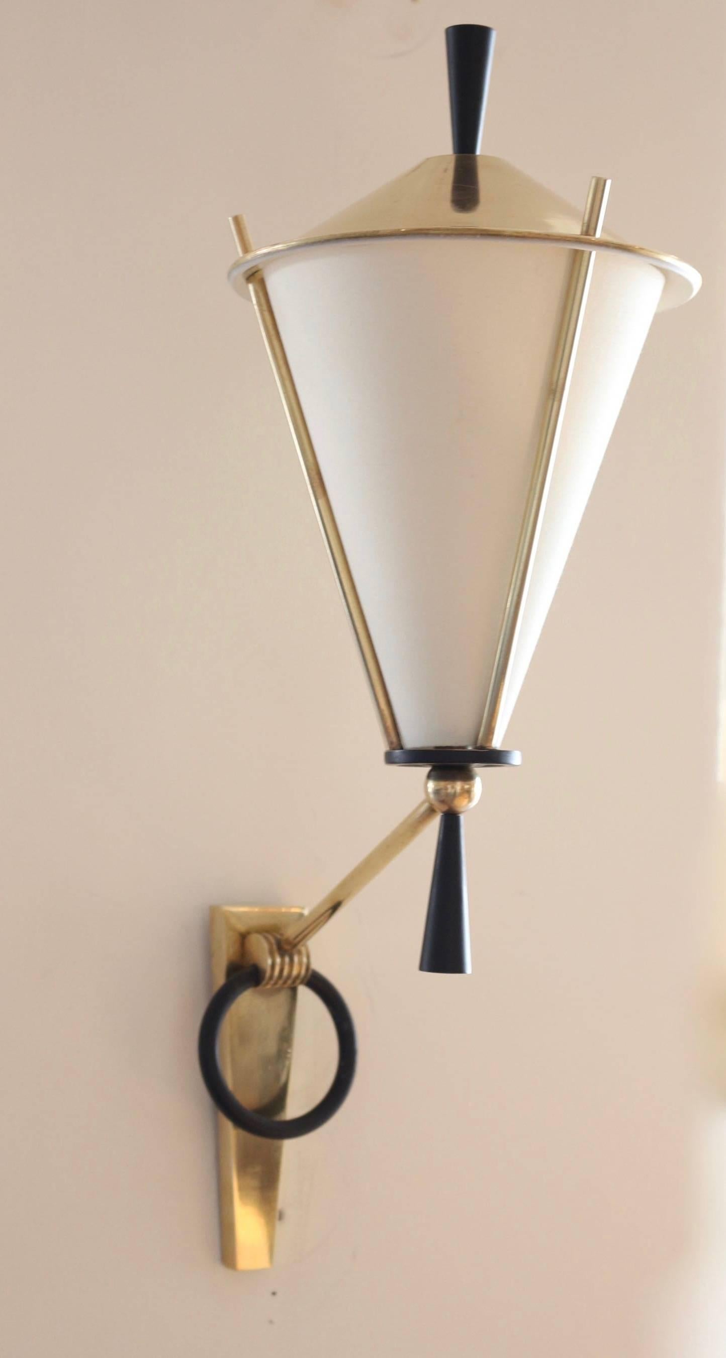 Set of three 1950s sconces by Maison Arlus.
A pair of Each sconce consists of two lighted arms set on trapezoidal a gilt brass plate decorated with a blackened brass ring.
The third lantern like sconce completes the set.