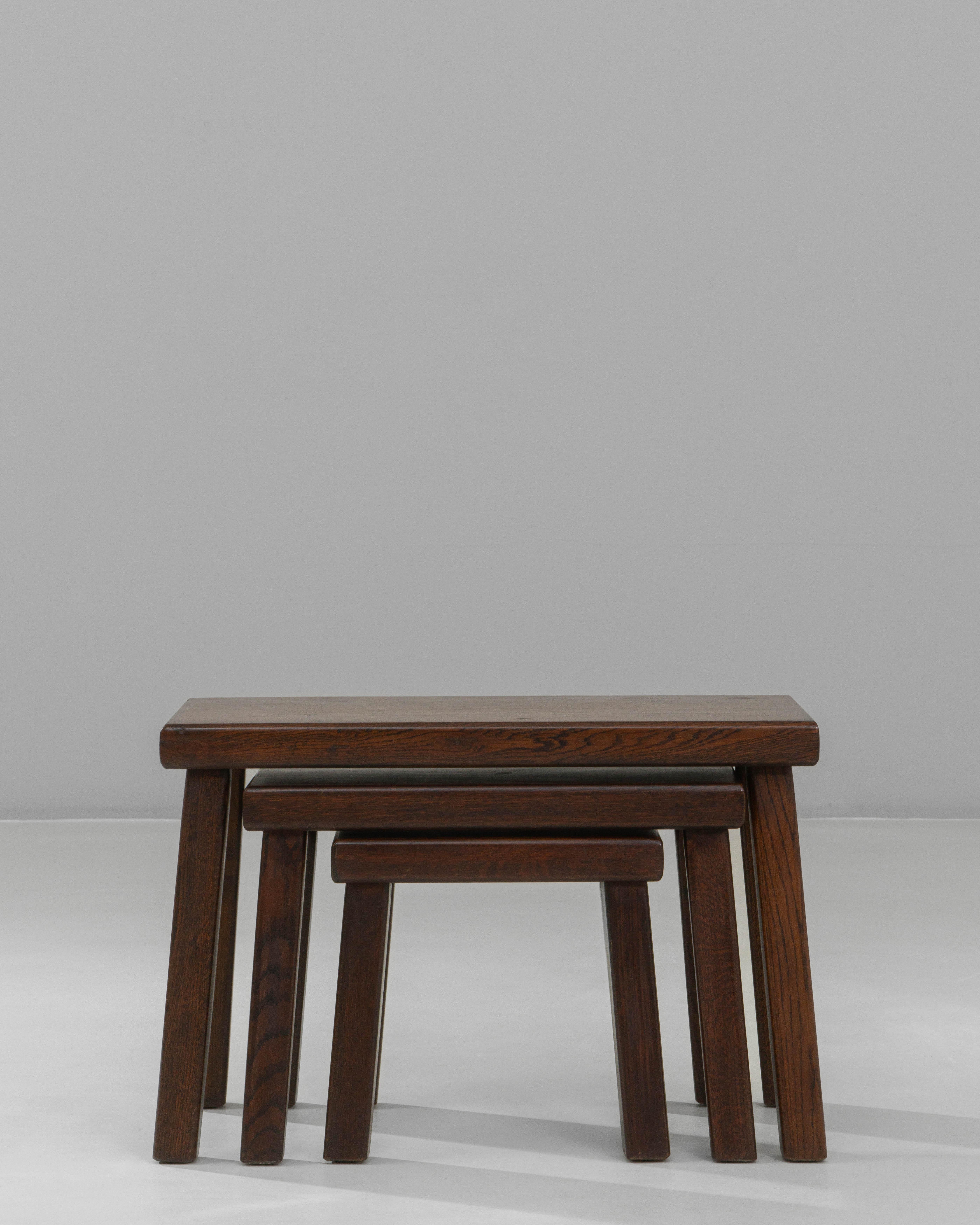 This set of three 1970s French Brutalist nesting tables showcases clean, purposeful lines and solid craftsmanship, emphasizing the weight and presence typical of the style. Each table features a thick, rectangular top supported by angled legs that