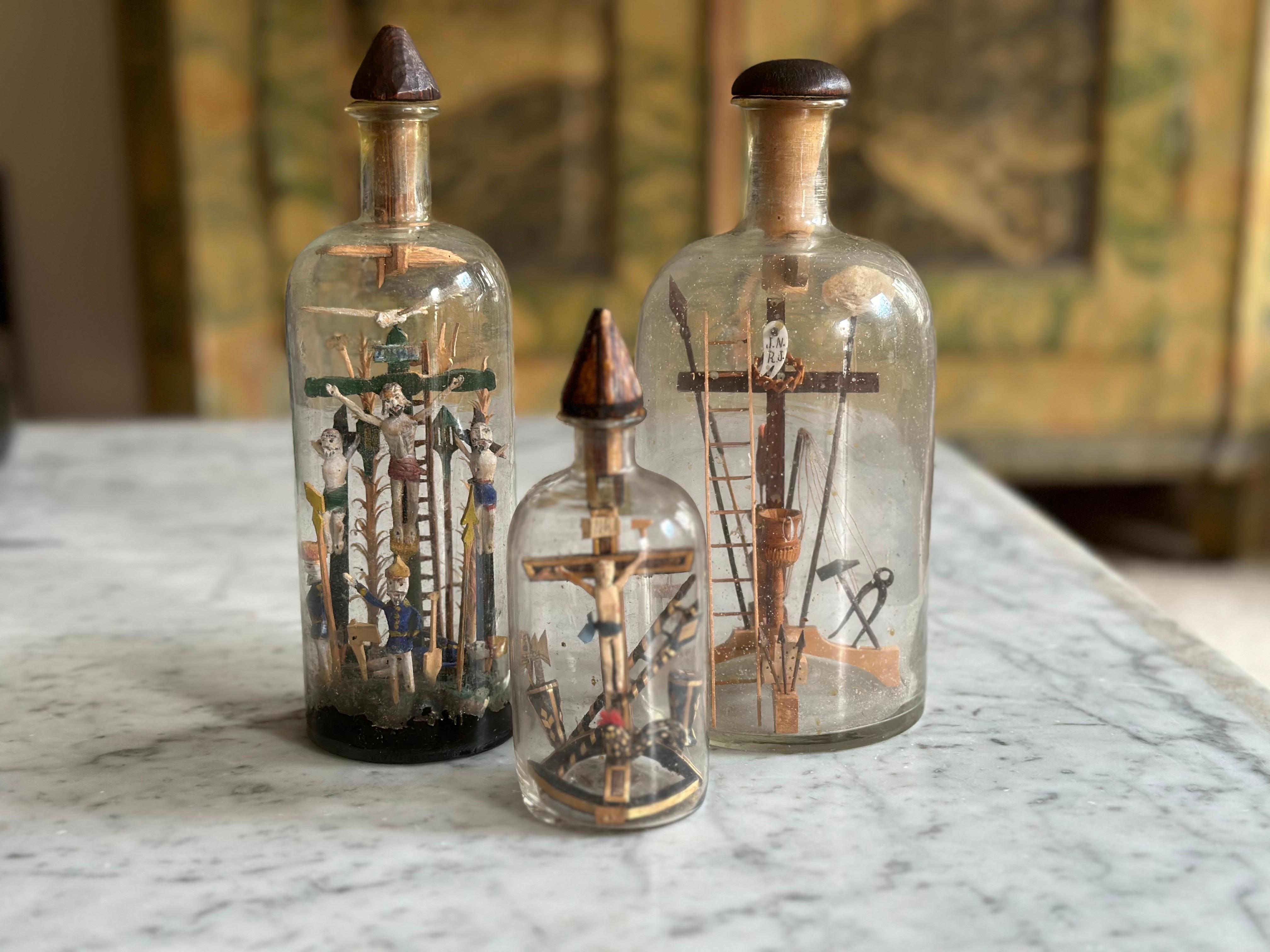 This rare set of three “Patience Bottles” (Geduldsflaschen), crafted in the Alpine regions in the late 19th century, showcases the remarkable skill and devotion of folk artisans from that era. Each bottle contains a delicate religious scene