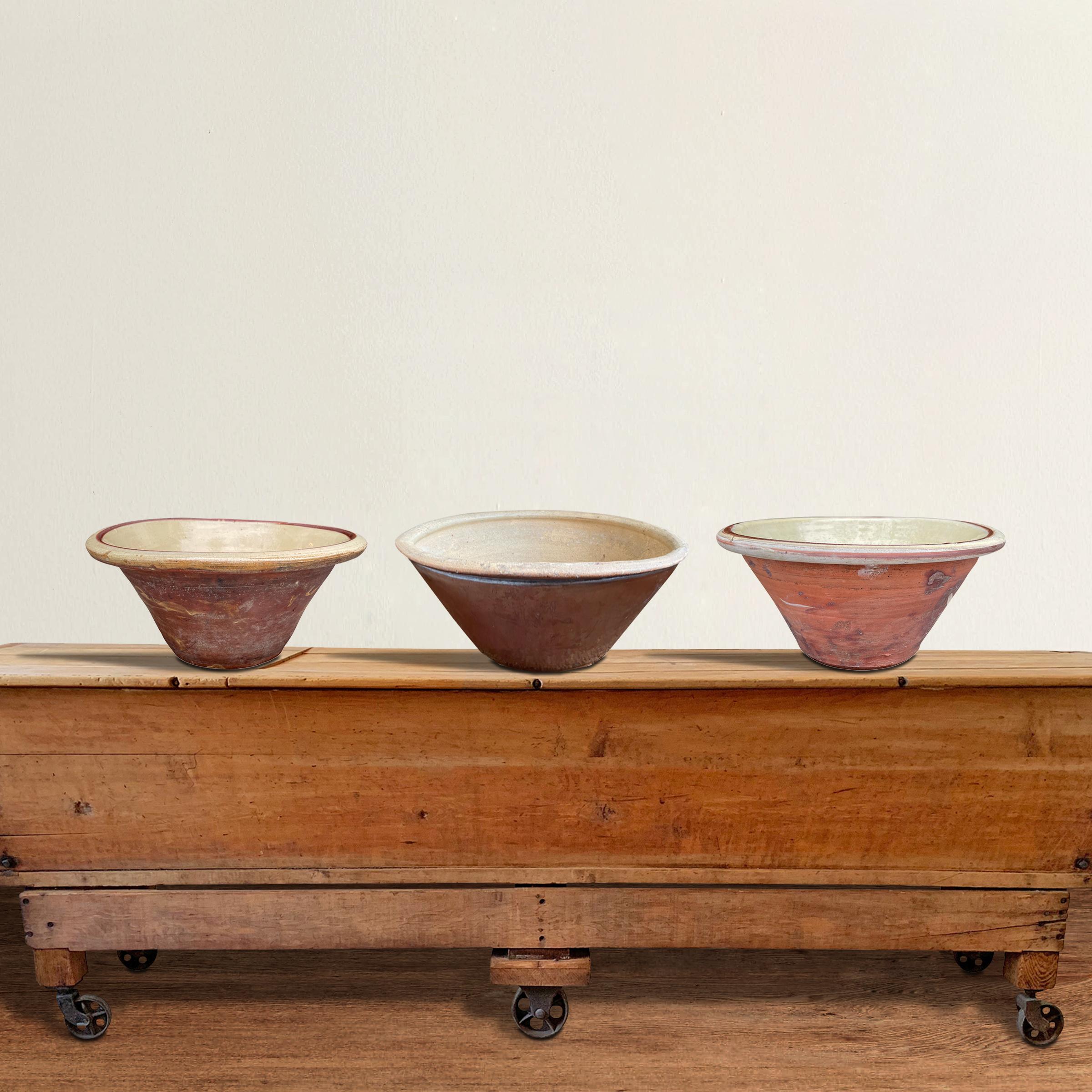 A chic set of three 19th century English glazed terra-cotta dough bowls, two with unglazed exteriors with white crackle glazed interiors, and one with a brown glazed exterior and an unglazed interior with a textured interior meant to transfer a