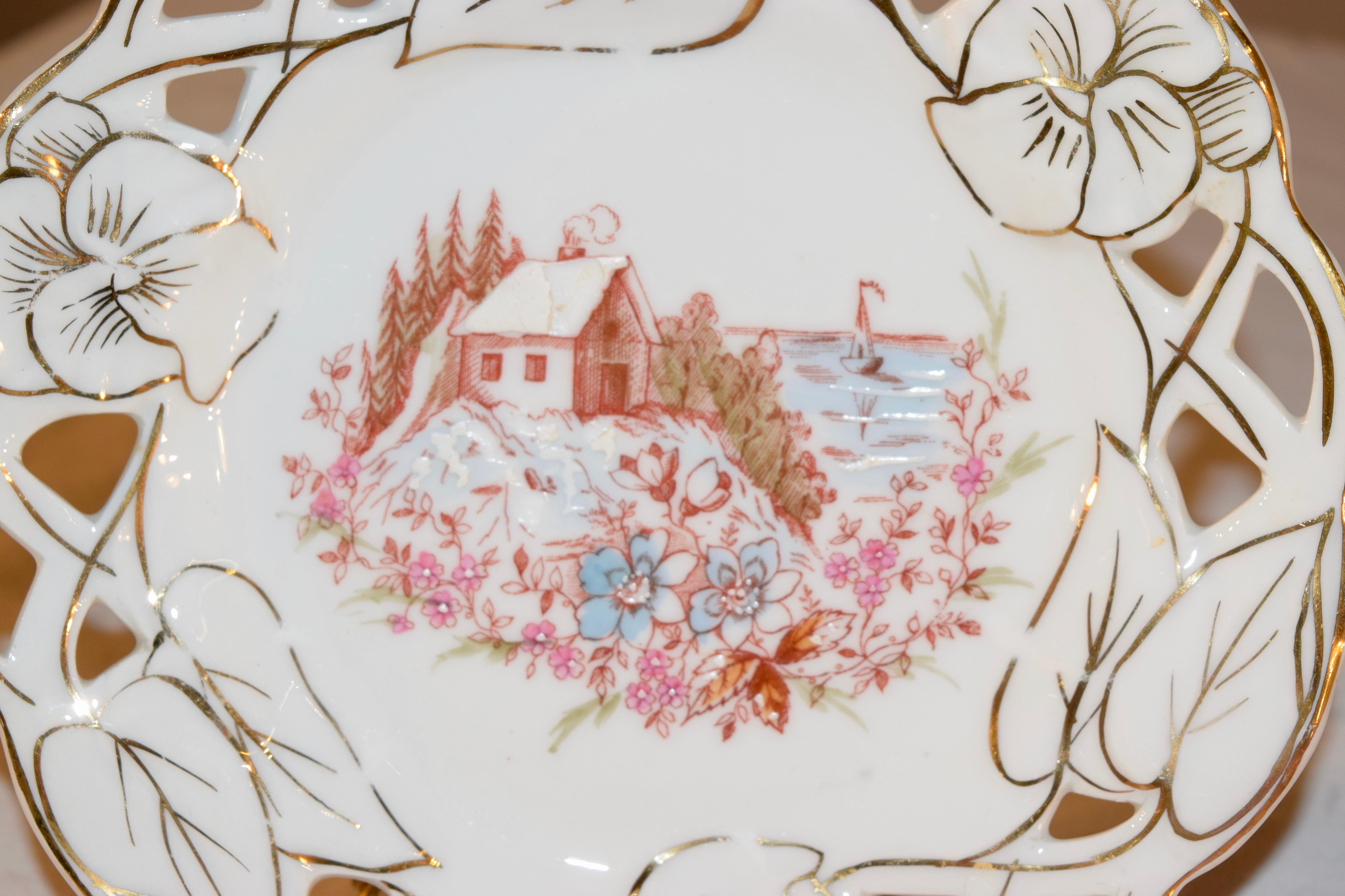 Set of three 19th century porcelain plates from France with pierced and molded borders, which have been enhanced with gilt accents. The central scenes are transferred and hand painted with village ocean scenes.