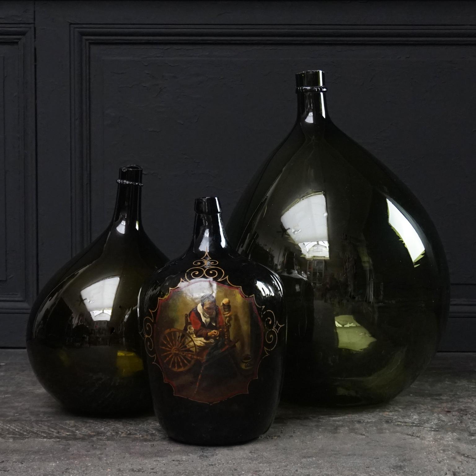Wonderful set of three Italian different shades of green, blown wine bottles.
Also known as Dame Jeanne, Damigiana, Demijohn, Carboy or Bonbonne bottles.

All three are hand blown, the larger ones have cut necks, the small hand painted one was blown