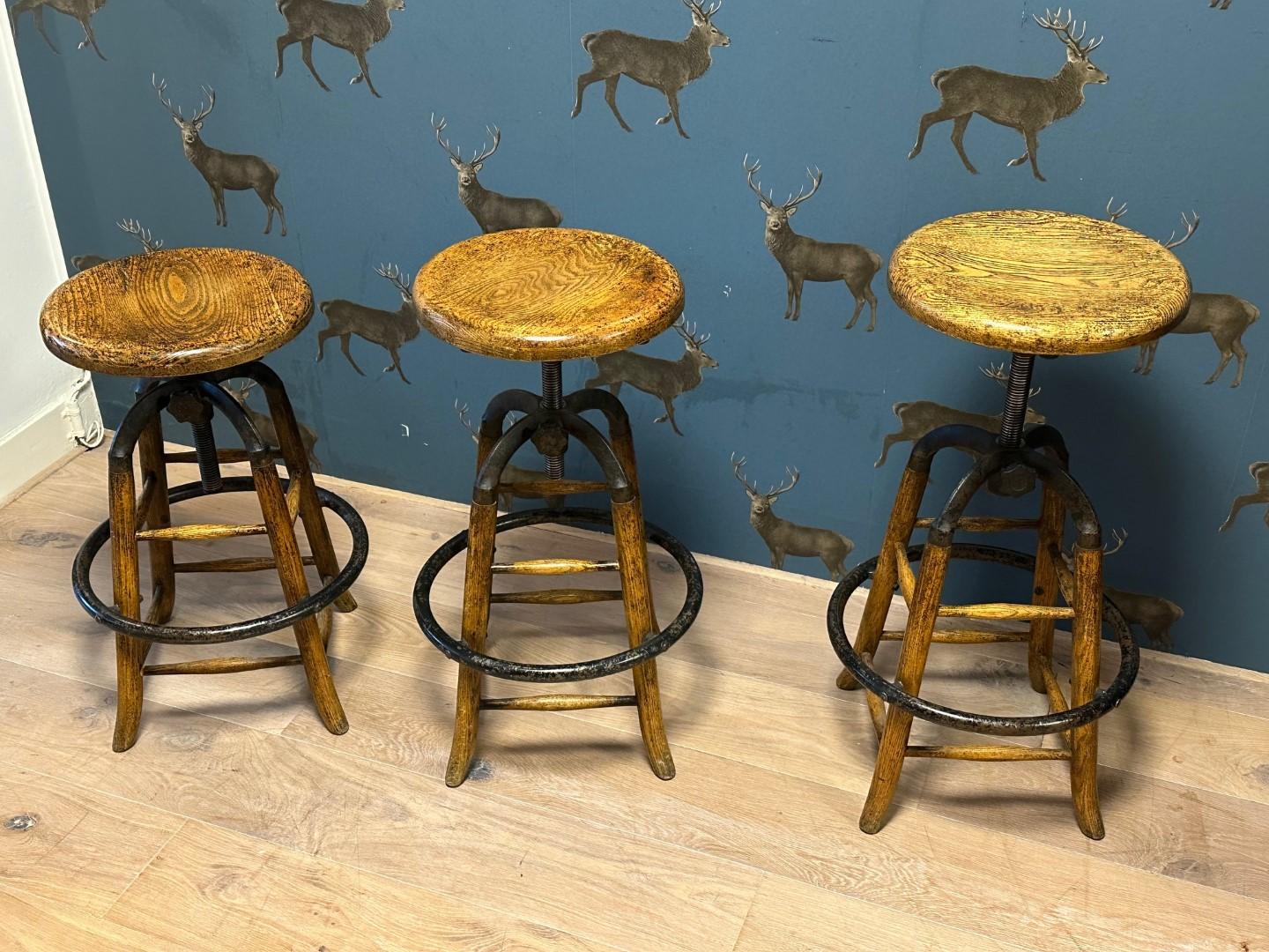 Set of 3 industrial stools which are adjustable in height. Combination of oak, cast iron and iron.  Not antique. In very good condition.

Average seat 35cm H. 65cm - 83cm