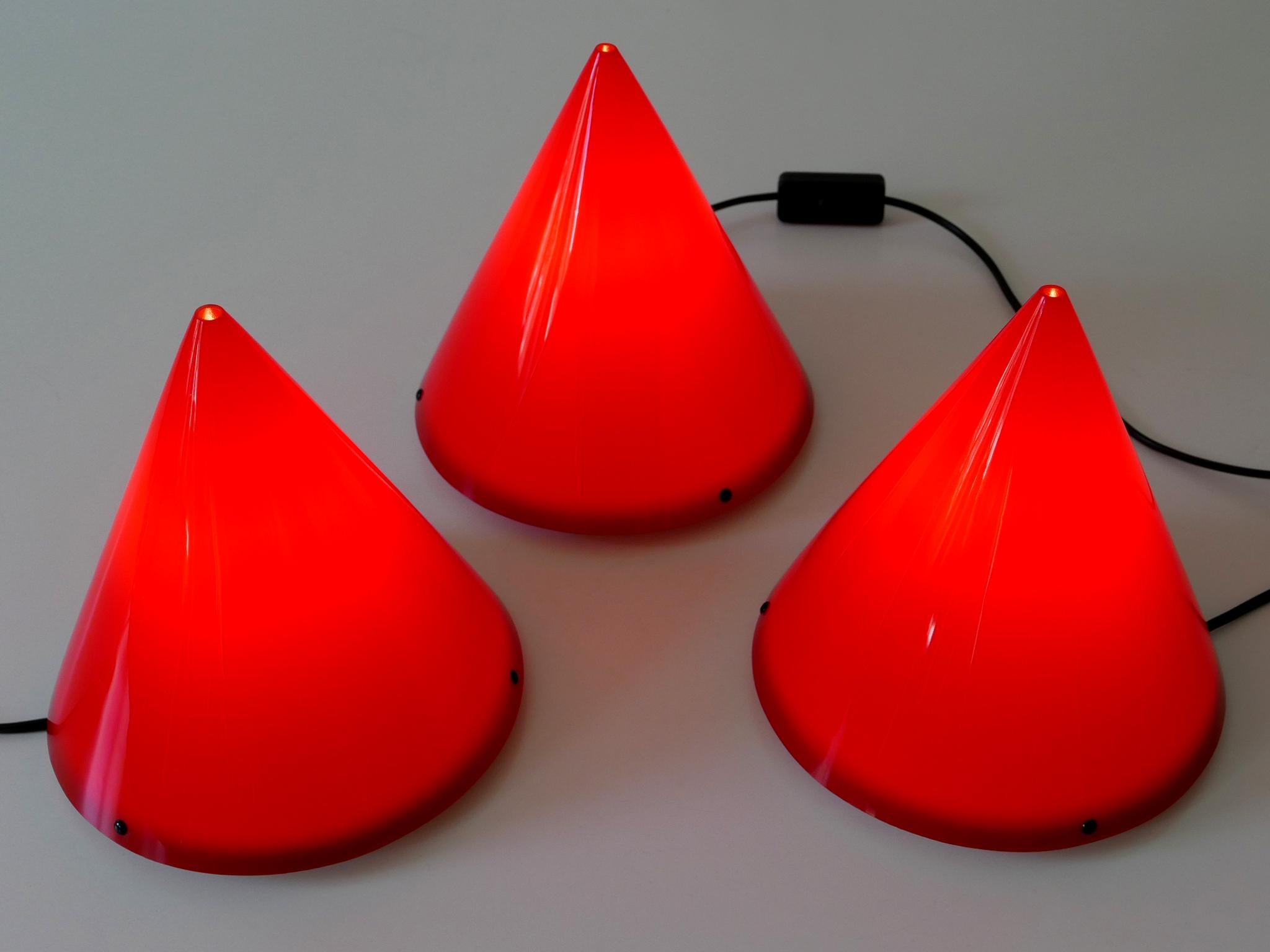 Set of three lovely Modernist table lamps or sconces 'Cone' in red acrylic. Designed by Verner Panton in 1995. Manufactured by Poly Thema in a small edition (300 of each color). Each cone will be mounted to the white base by three black circular