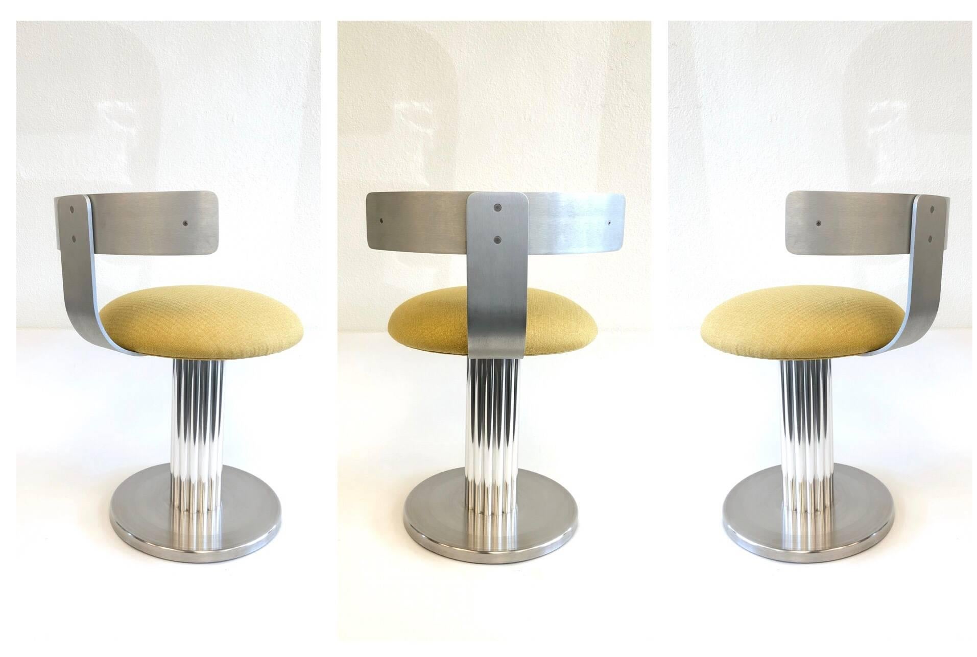 A set of three aluminium and stainless steel swivel stools by Design For Leisure Ltd. This are from the 1980s newly recovered in a beautiful yellow fabric. The stools are constructed of stainless steel and aluminium. The backrest is brush aluminium,