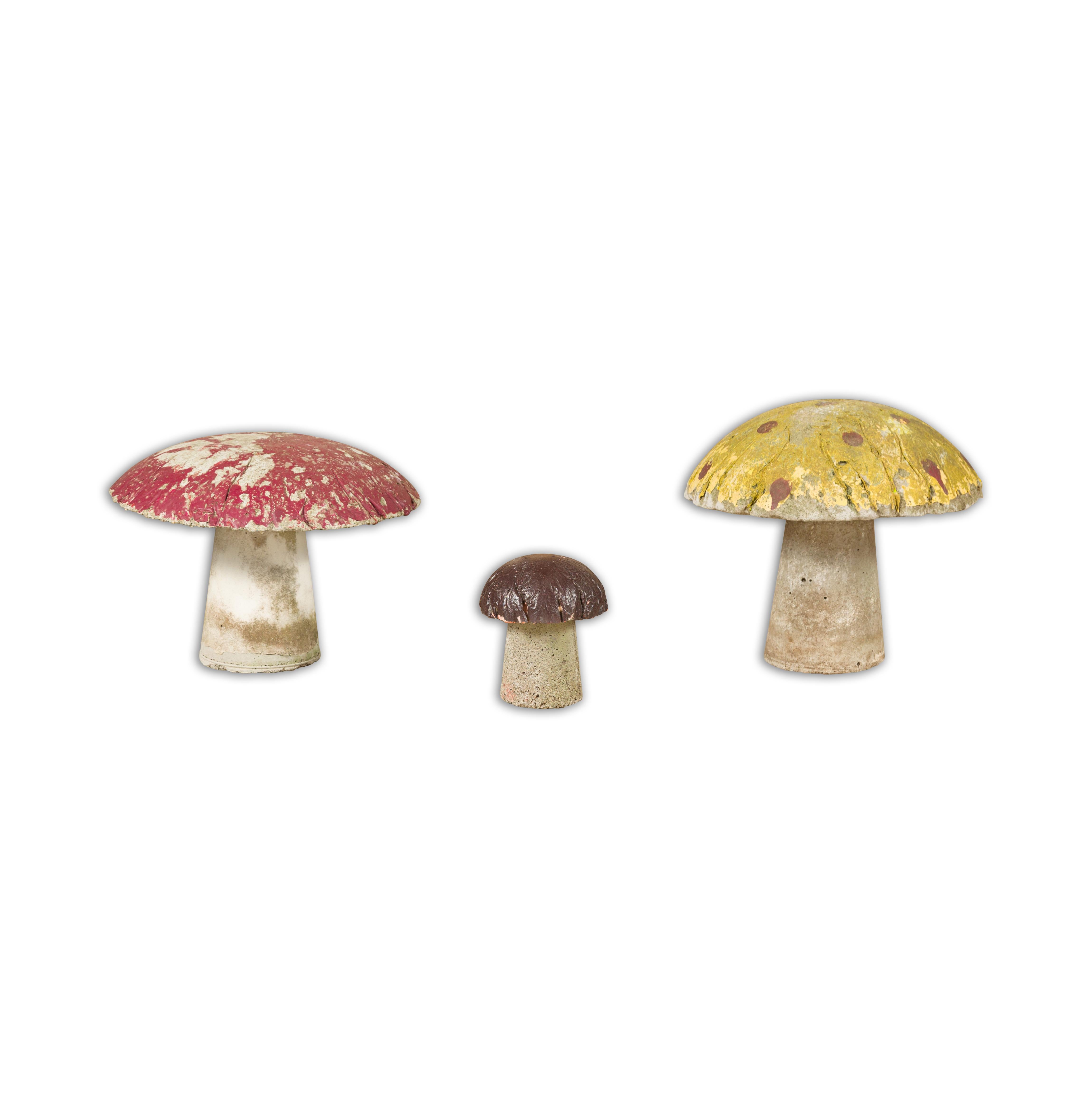 A set of three American Midcentury painted concrete mushroom garden ornaments with red, yellow and brown paint and nicely weathered appearance. Invite a touch of fantasy into your garden with this charming set of three American Midcentury painted