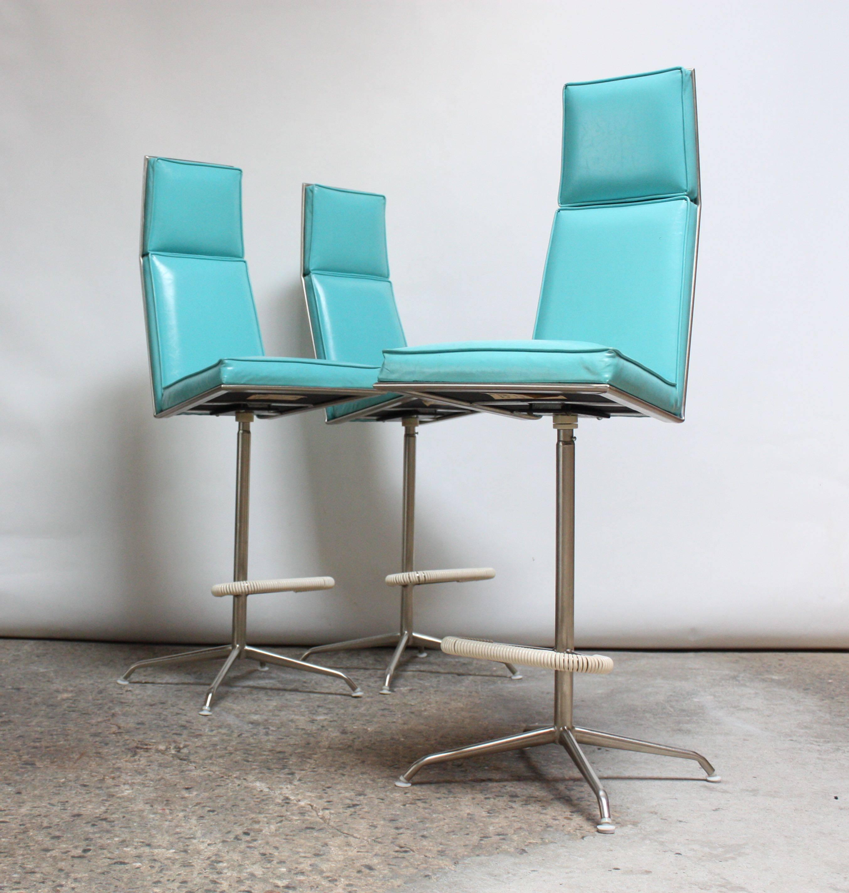 Set of three swivelling barstools composed of turquoise vinyl and brushed aluminium frames with cord-wrapped footrests.
Designed and manufactured by Jansko (USA, 1960s). Each stool retains the 'Jansko' fabric tag to the underside.
Minor wear to