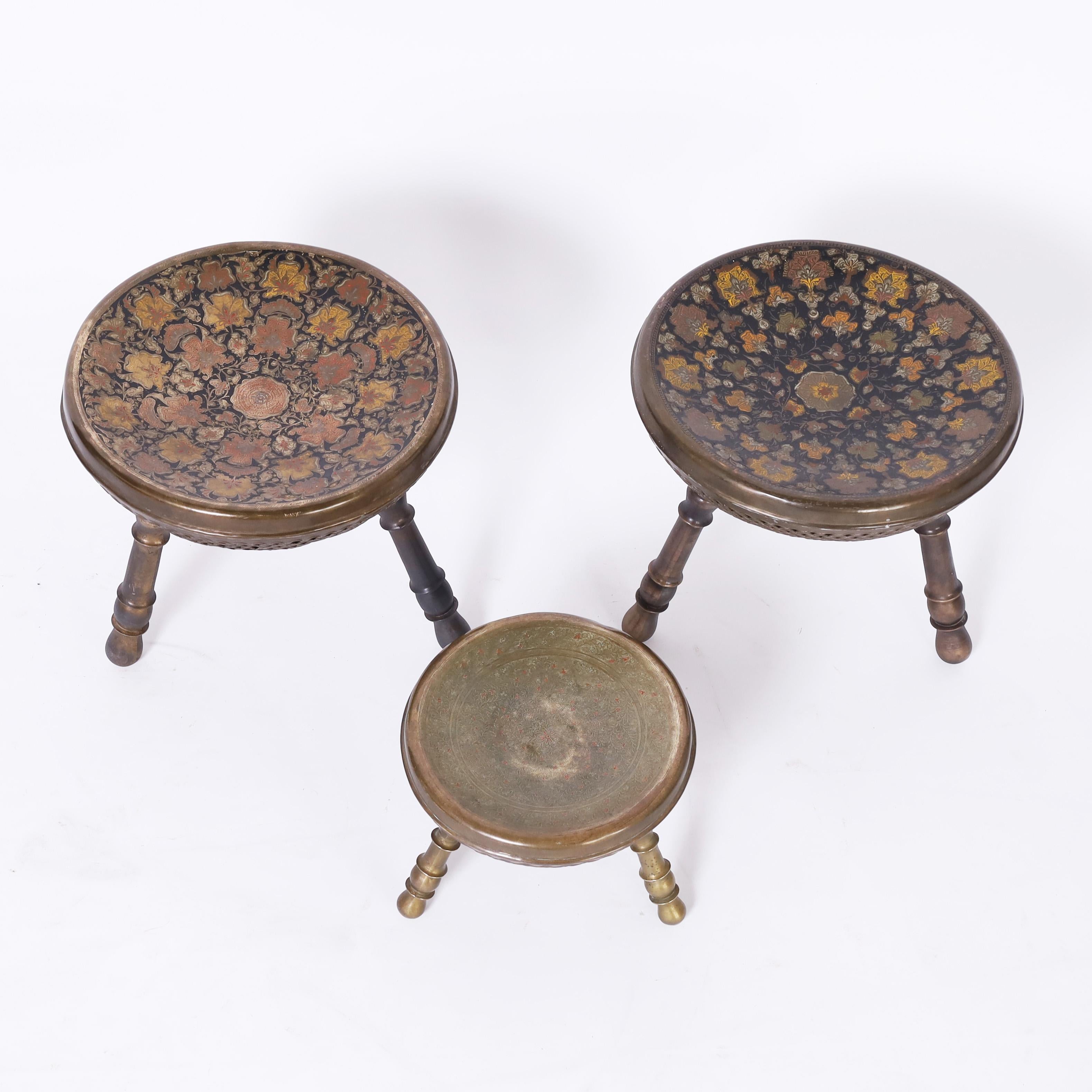 Vintage set of three Anglo Indian foot stools having a pair and a single crafted in brass and decorated with enamel in lovely floral motifs. 

Pair measures H: 11.5 DM: 12
Single measures H: 7 DM: 9