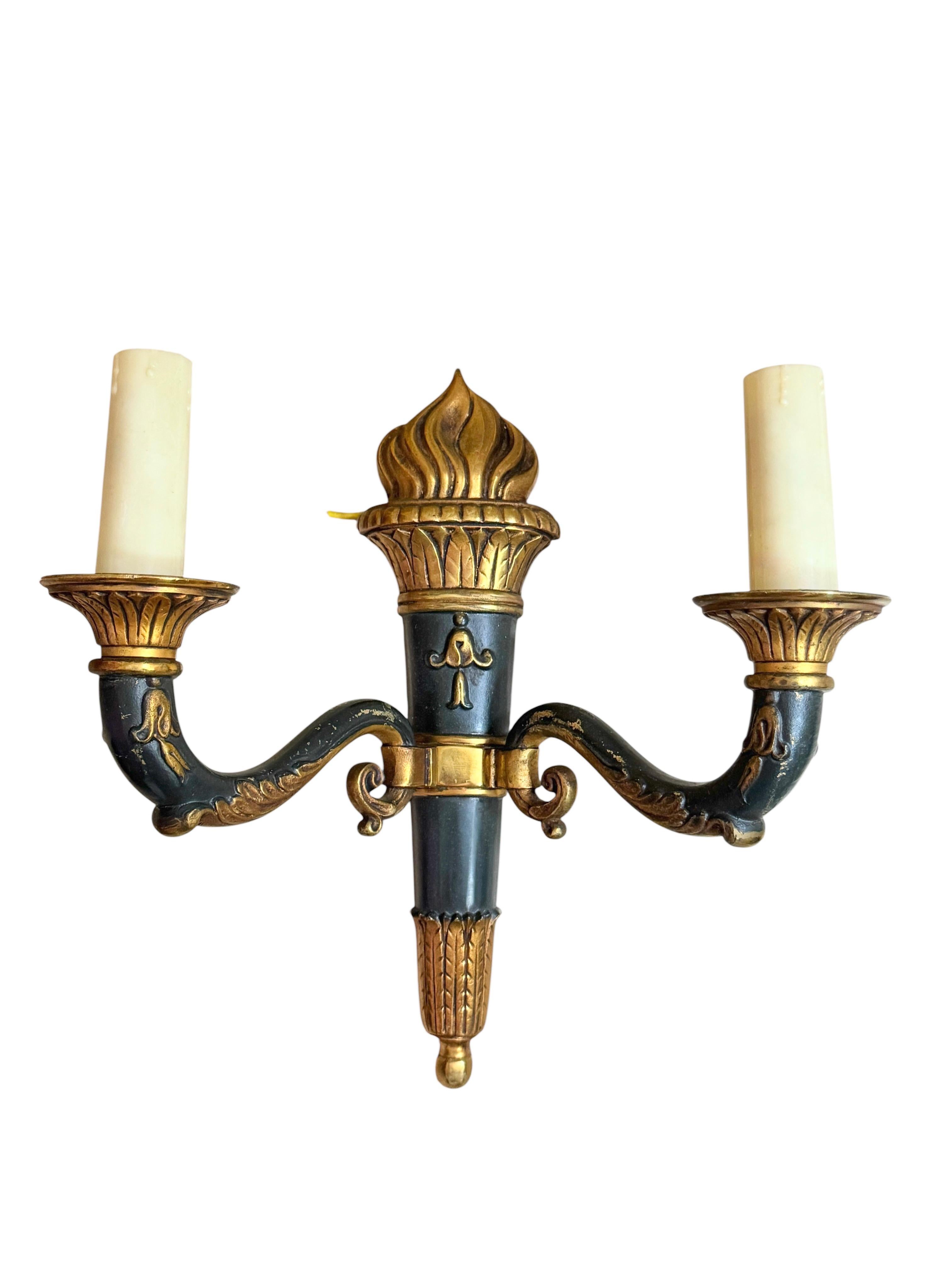 Un bonito conjunto de tres apliques con 2 fuentes de luz, fabricados en bronce en estilo antorcha. Cada aparato requiere dos bombillas candelabro europeas E14 de hasta 40 vatios cada una. Los apliques tienen una hermosa pátina y dan a cada