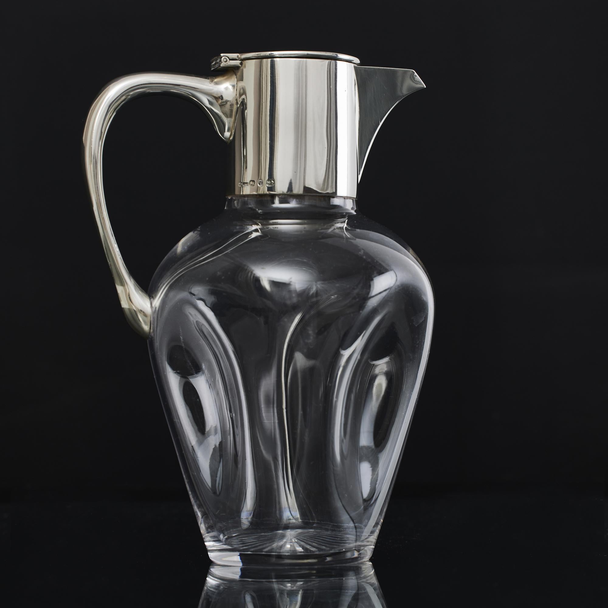 Antique, late-Victorian-era wine jug whose hand blown pinched plain glass body is very pleasingand silver mounts. The base is cut with a starburst pattern.