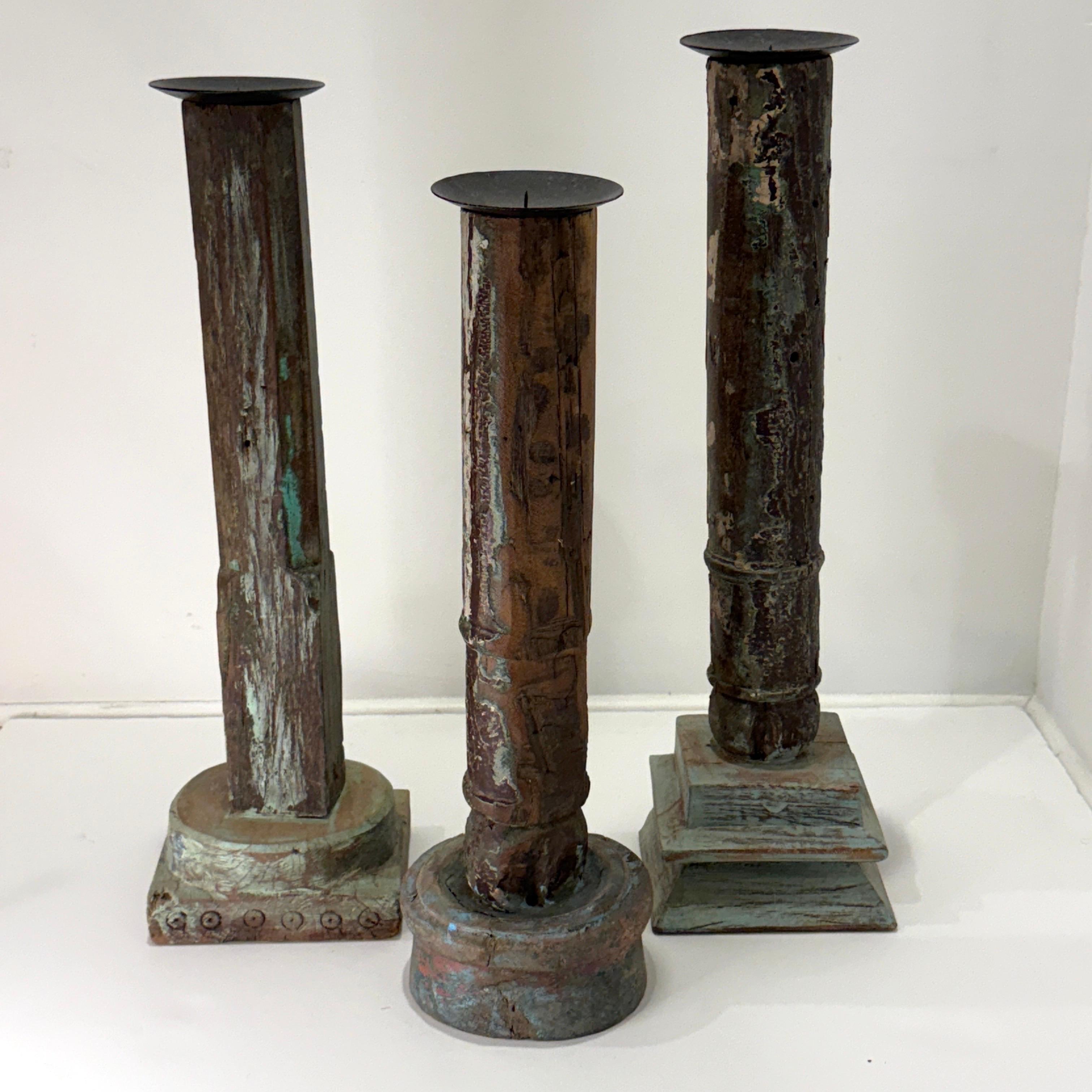 Ensemble de trois piliers rustiques en bois sculpté et récupéré. Les colonnes sont toutes uniques et présentent des socles différents avec des sculptures et des motifs distincts.  Les bases et les colonnes présentent également une peinture vieillie