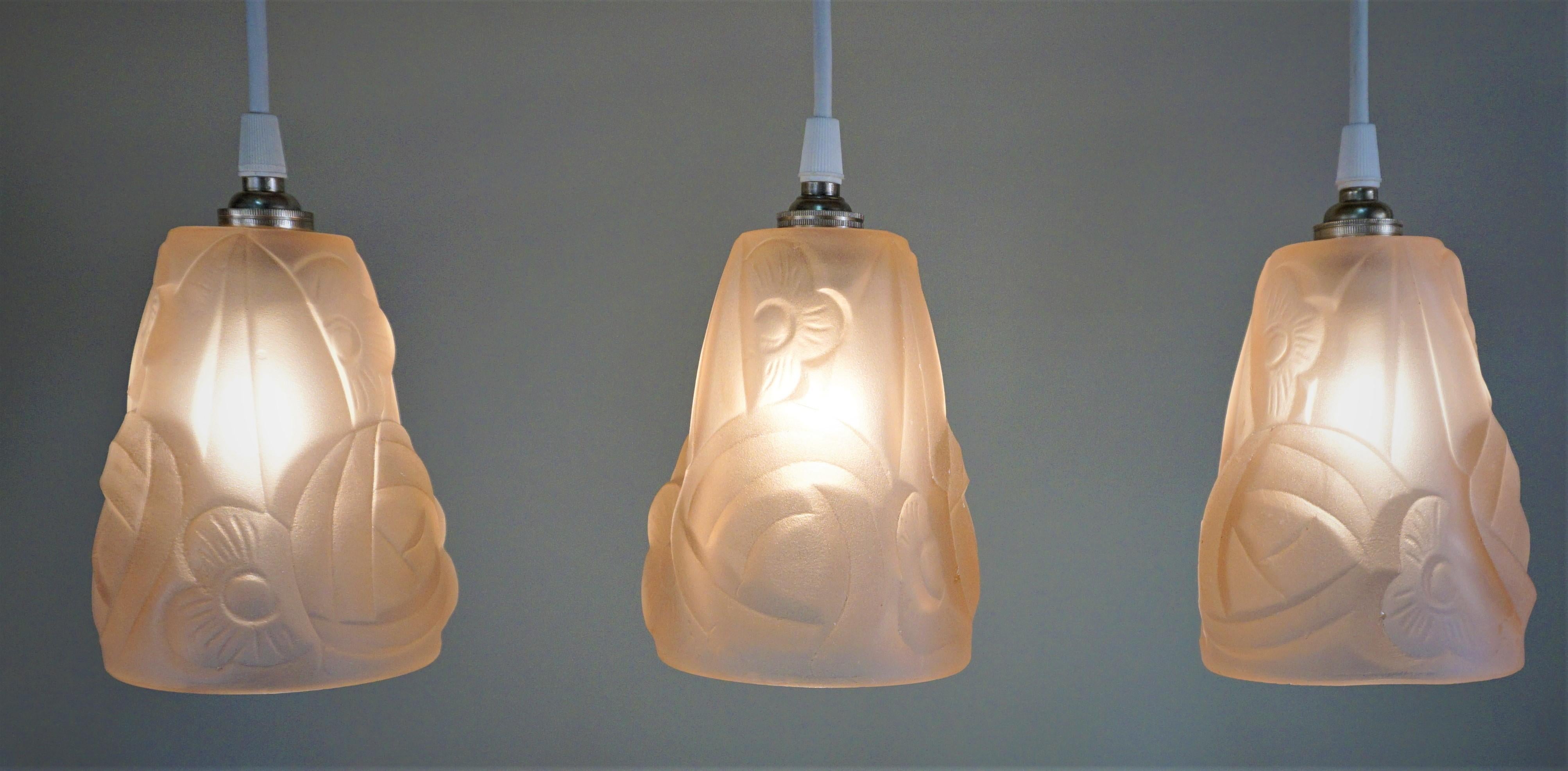 Set of three Art Deco clear Mauve/pink glass shades by Degue that have been modified with new white cord and nickel canopy as pendant lights.

Price is for set of 3.