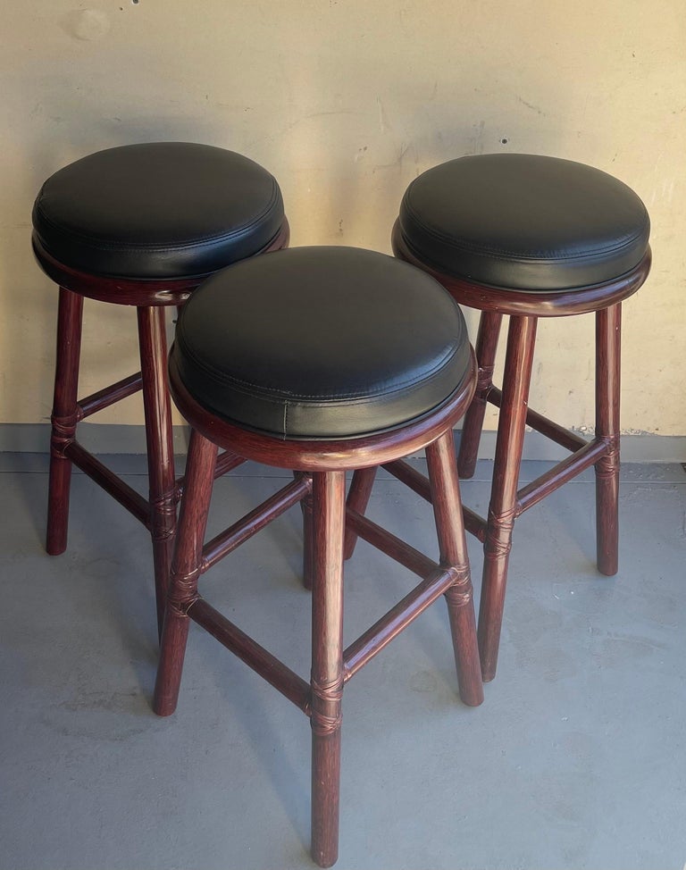 Set of three bamboo and leather bar stools by McGuire Furniture Co. of San Francisco, circa 1990s. These stools are difficult to find and are in good vintage condition. Each one measures 15.5