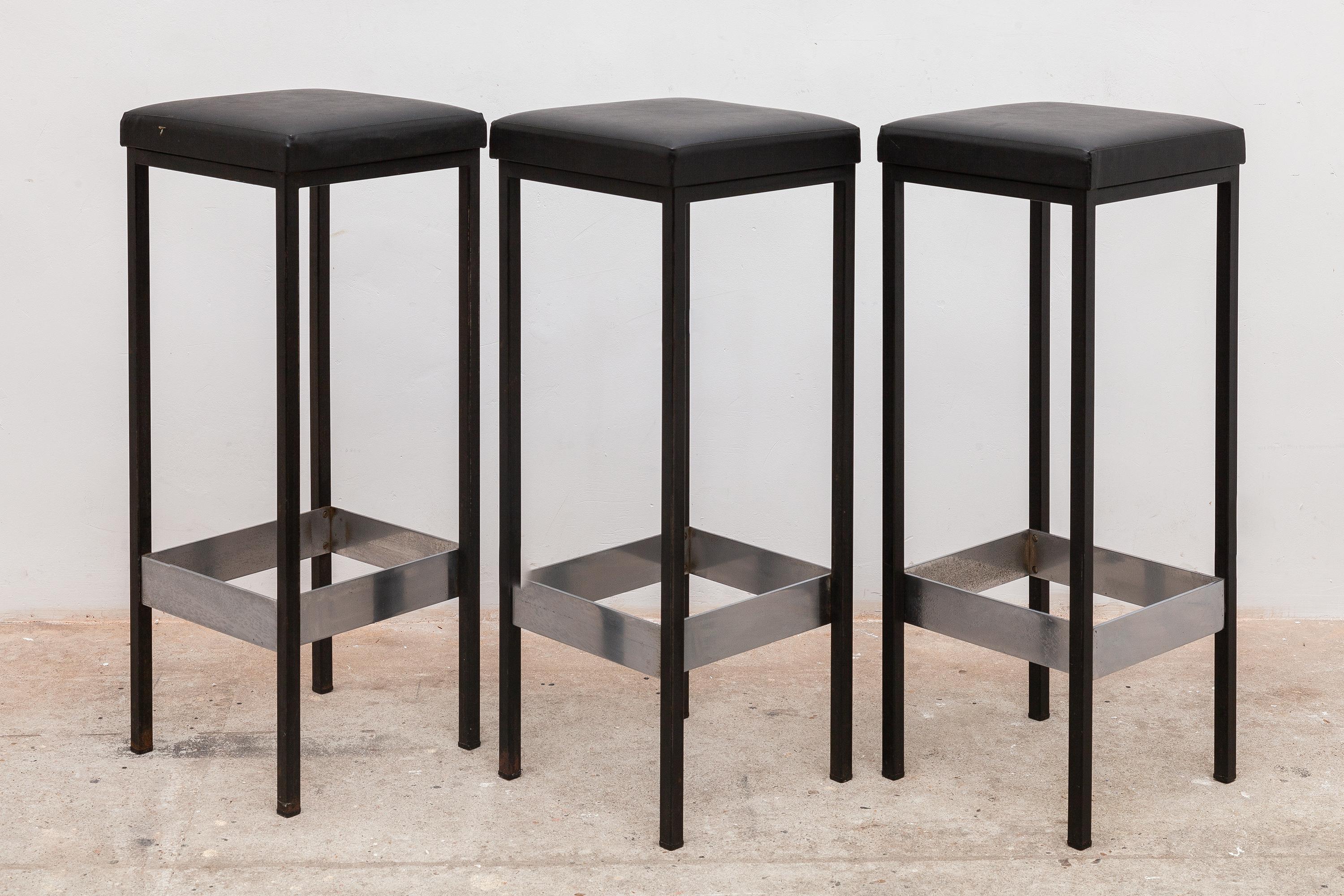 Set of three vintage bar stools with original black vinyl upholstery. Strong black iron bases with chrome leg braces. 
Dimensions: 31 W x 79 H x 31 D cm.
