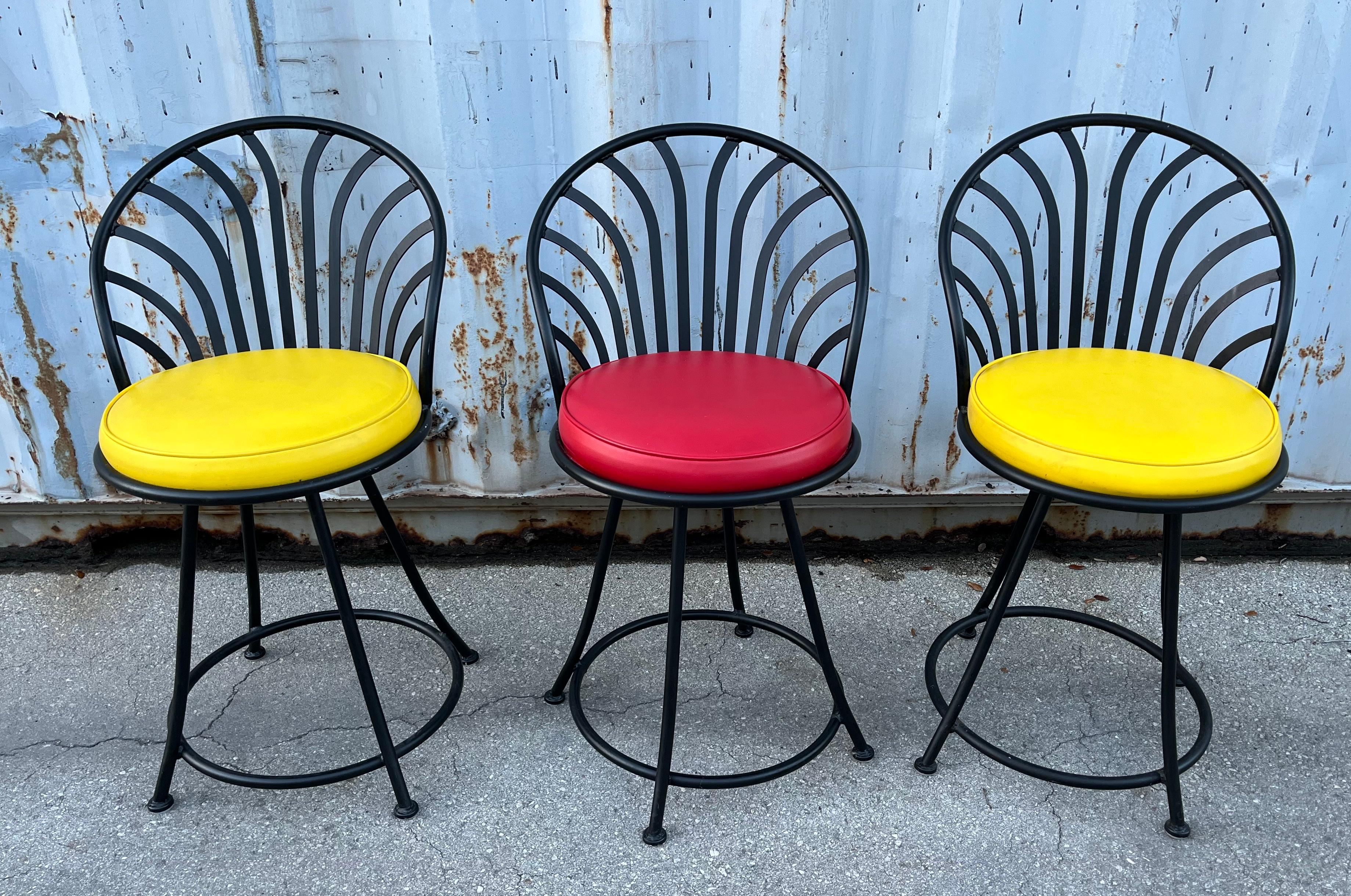 Set of Three Mid Century Modern Swivel Stools by Arthur Umanoff for Shaver Howard Furniture. Circa 1970s.
Features forged steel frames and swivel seats with the original vinyl upholstery in yellow. 
In good original condition with minor signs of
