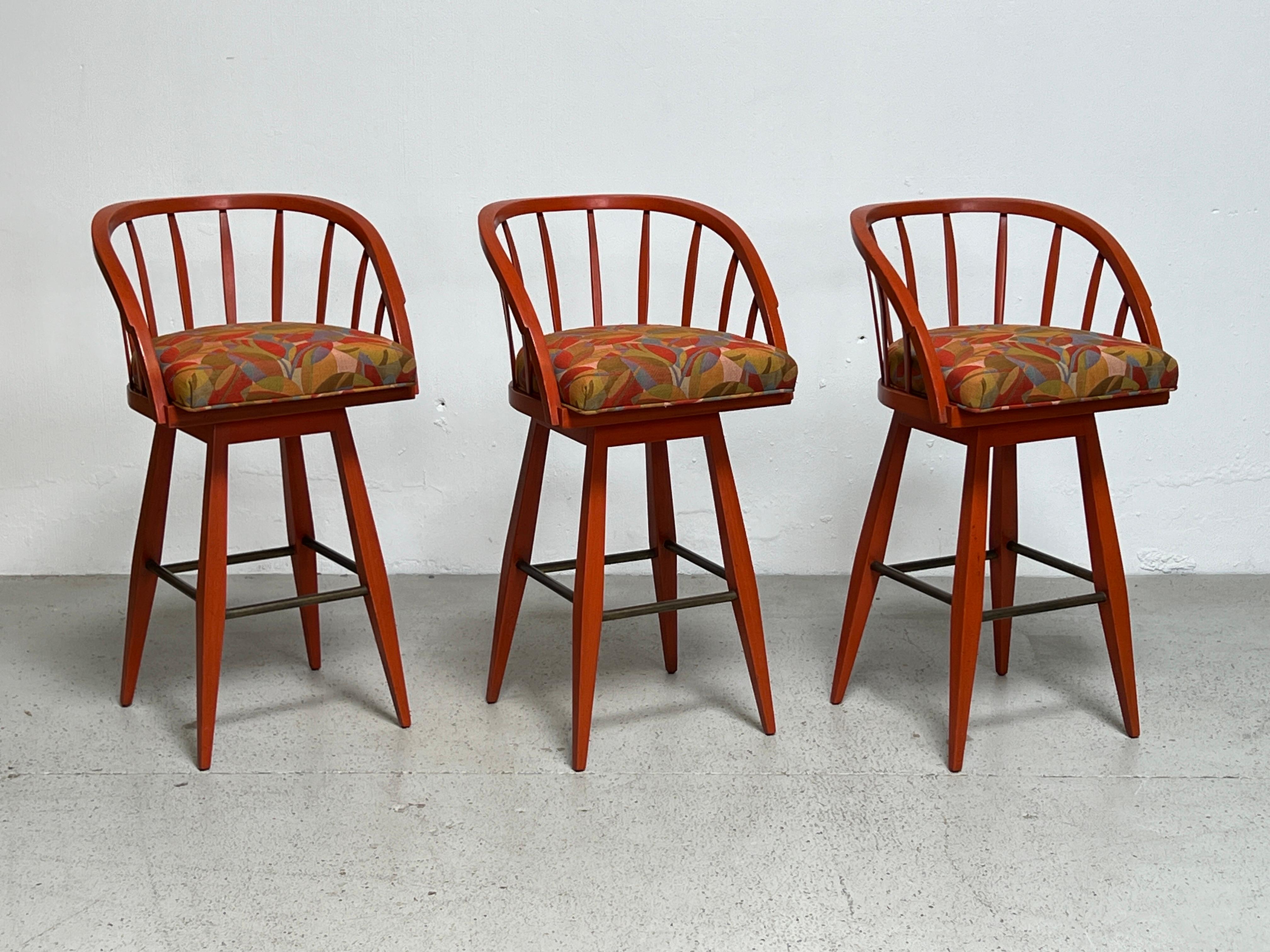 A set of three swiveling barstools designed by Edward Wormley for Dunbar. Original lacquer finish. Reupholstered in vintage Dunbar fabric. 