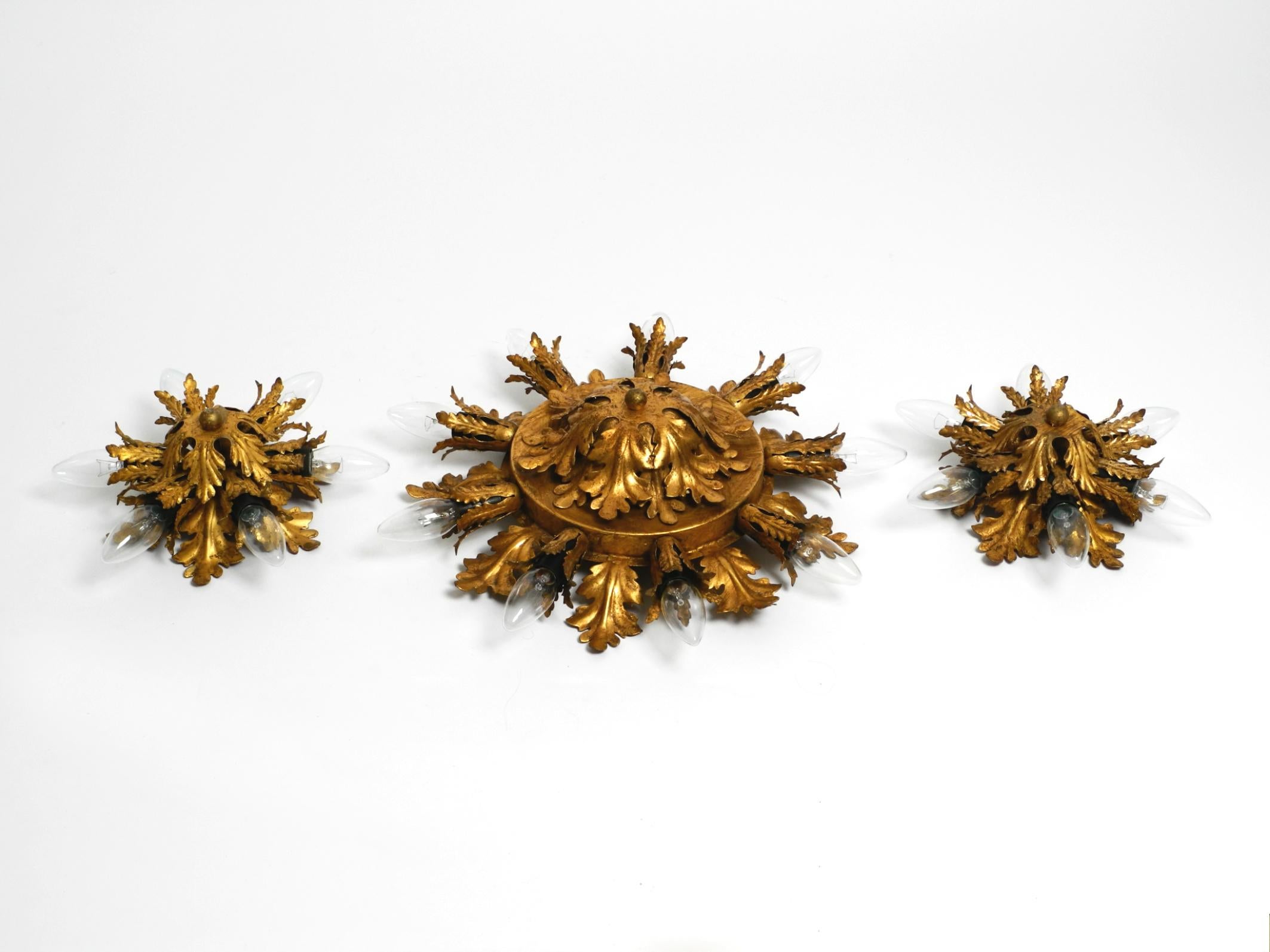 Set of three elegant, rare 1960s Florentine ceiling or wall lamps.
Manufacturer is Banci Firenze. Made in Italy.
Very elegant Italian design made entirely of gold-plated metal.
The large lamp has nine E14 sockets up to 40W. The two small ones each