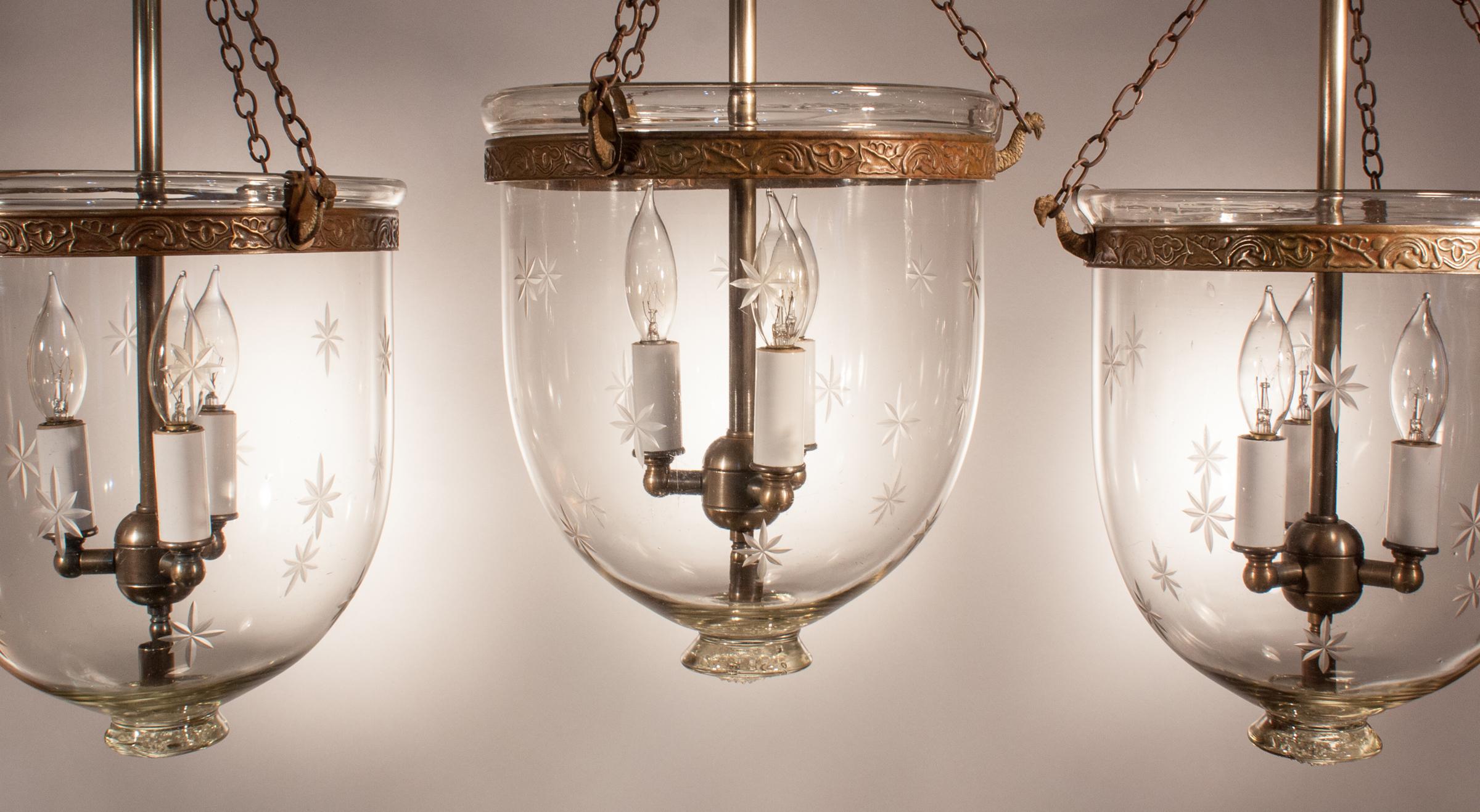 A rare, well-matched set of three antique English bell jar lanterns with an etched star motif, circa 1910. These charming lanterns have their original smoke bells/lids; however, the embossed brass bands and chains have been replaced for the security
