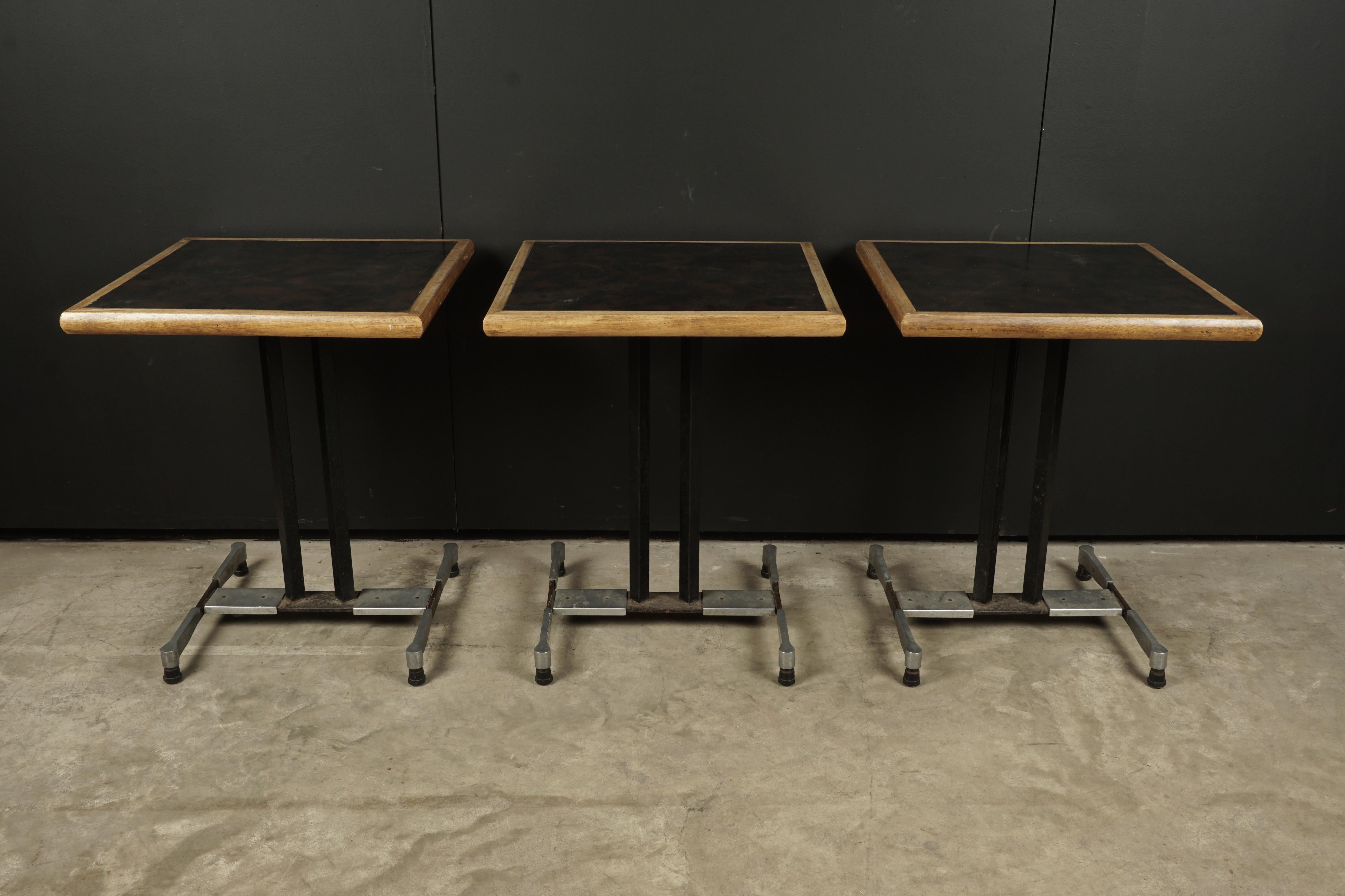 Vintage set of three Bistro tables from France, 1950s. Art Deco base of steel. Oak and metal top with light wear and patina.
