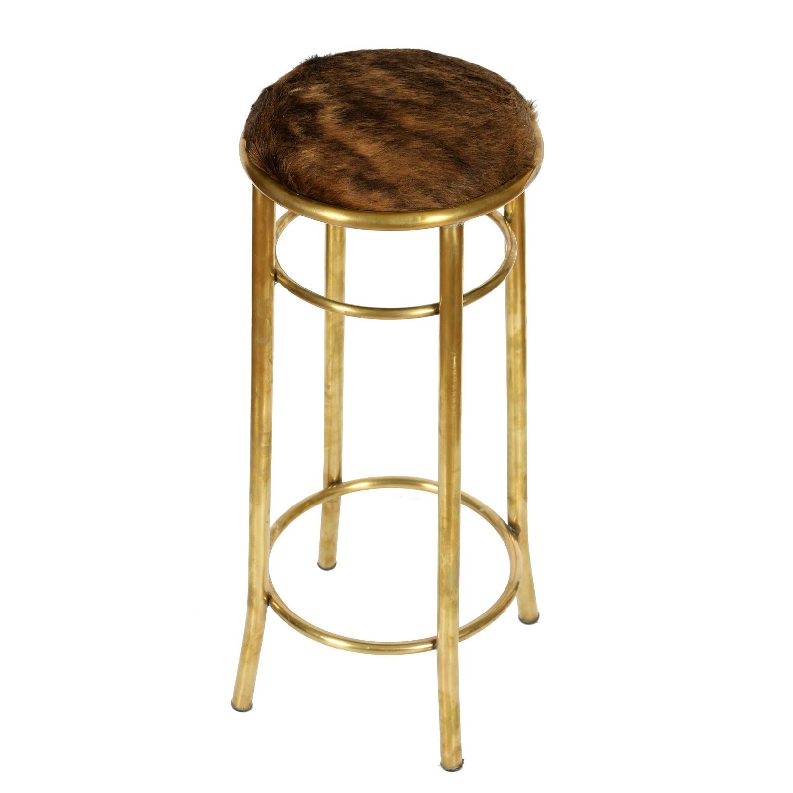 Mid-Century Modern set of three round barstools in brass with hide seats.