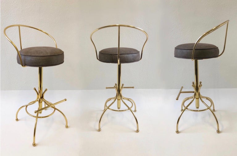 Set of three glamorous polish brass and suede leather ‘Sammy Davis” barstools. Design in the 1960s by Charles Hollis Jones. The seats swivel 360.
The frames have been newly polished and the seats have been newly recovered in a lite brown with a