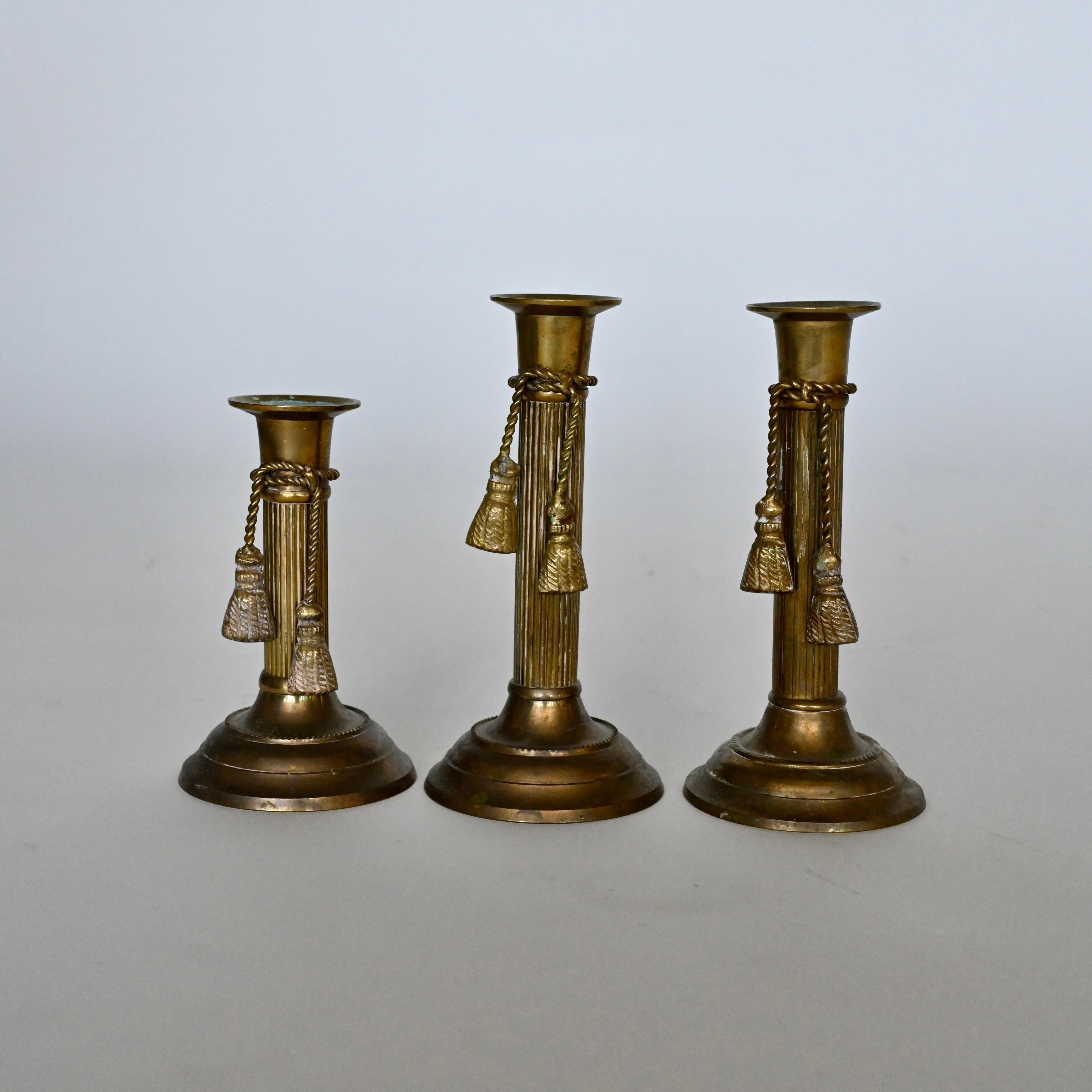 Metalwork Set of three brass candlesticks with tassel detail, mid 20th century. For Sale