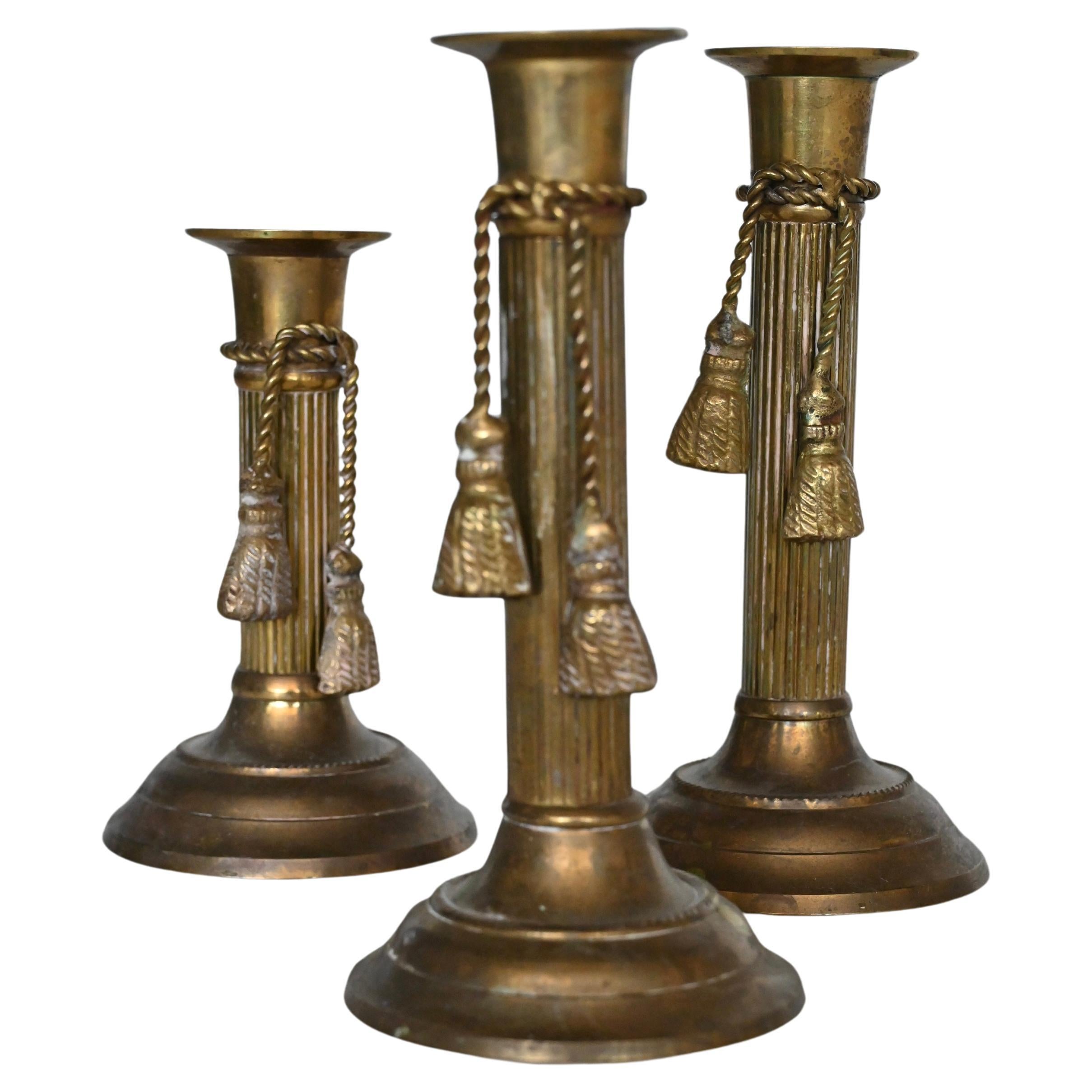 Set of three brass candlesticks with tassel detail, mid 20th century.