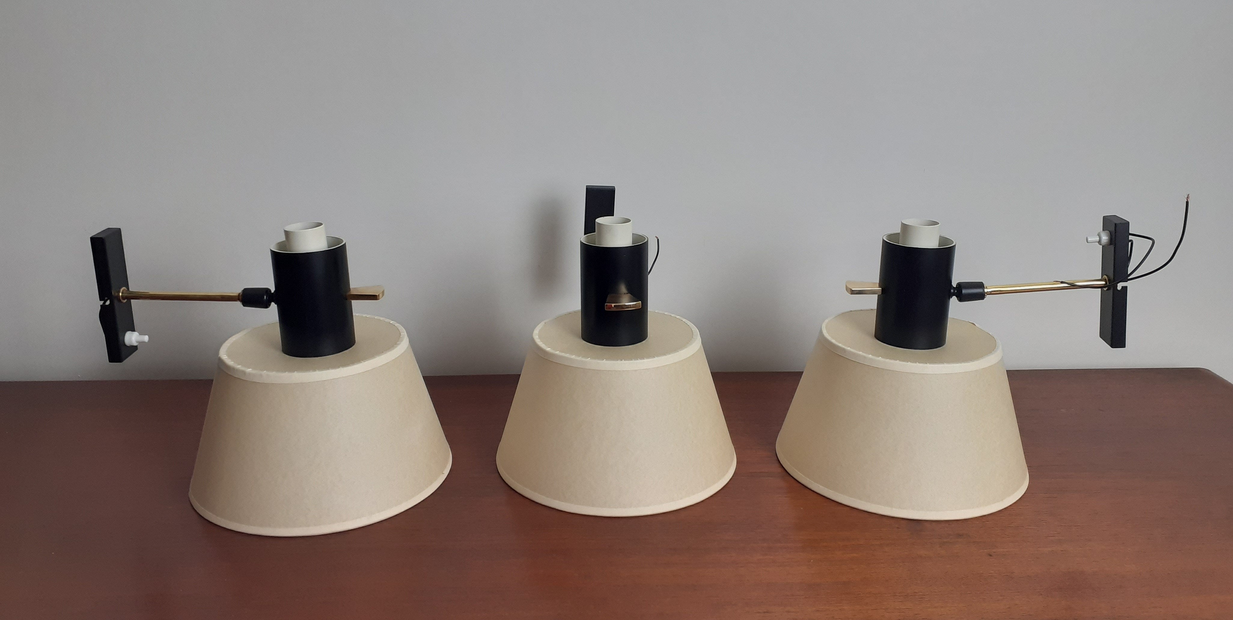 Set of 3 brass and lacquered metal wall lights composed of a rectangular black lacquered metal plate on which is placed a brass rod ending in a ball joint.
A tubular support in black lacquered metal and articulated by a ball joint serves as a base