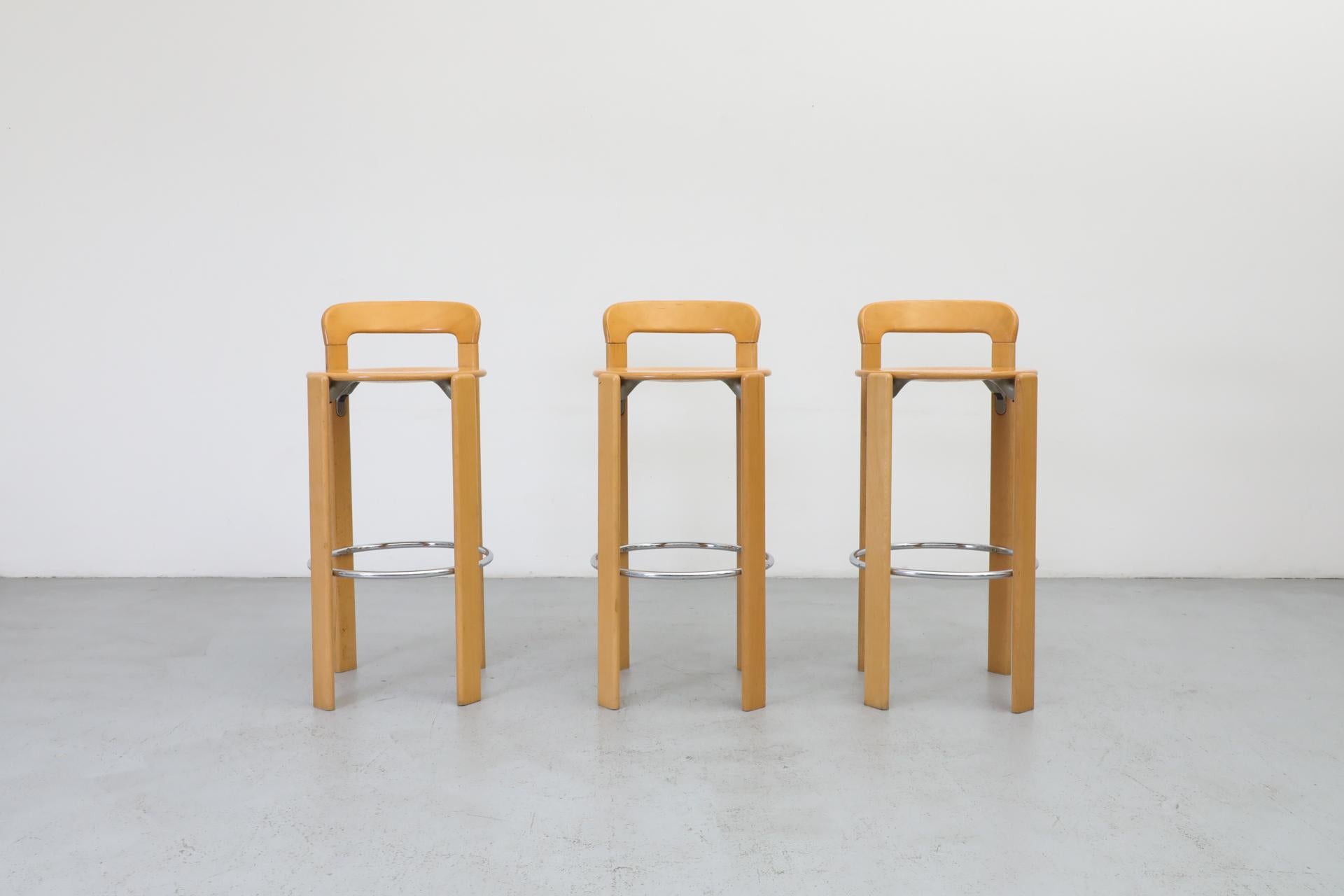 Conjunto de 3 taburetes de bar de haya diseñados por Bruno Rey para Dietiker. Respaldos pequeños y reposapiés redondos cromados. Históricamente, creada a partir de la silla suiza de mayor éxito jamás producida, 