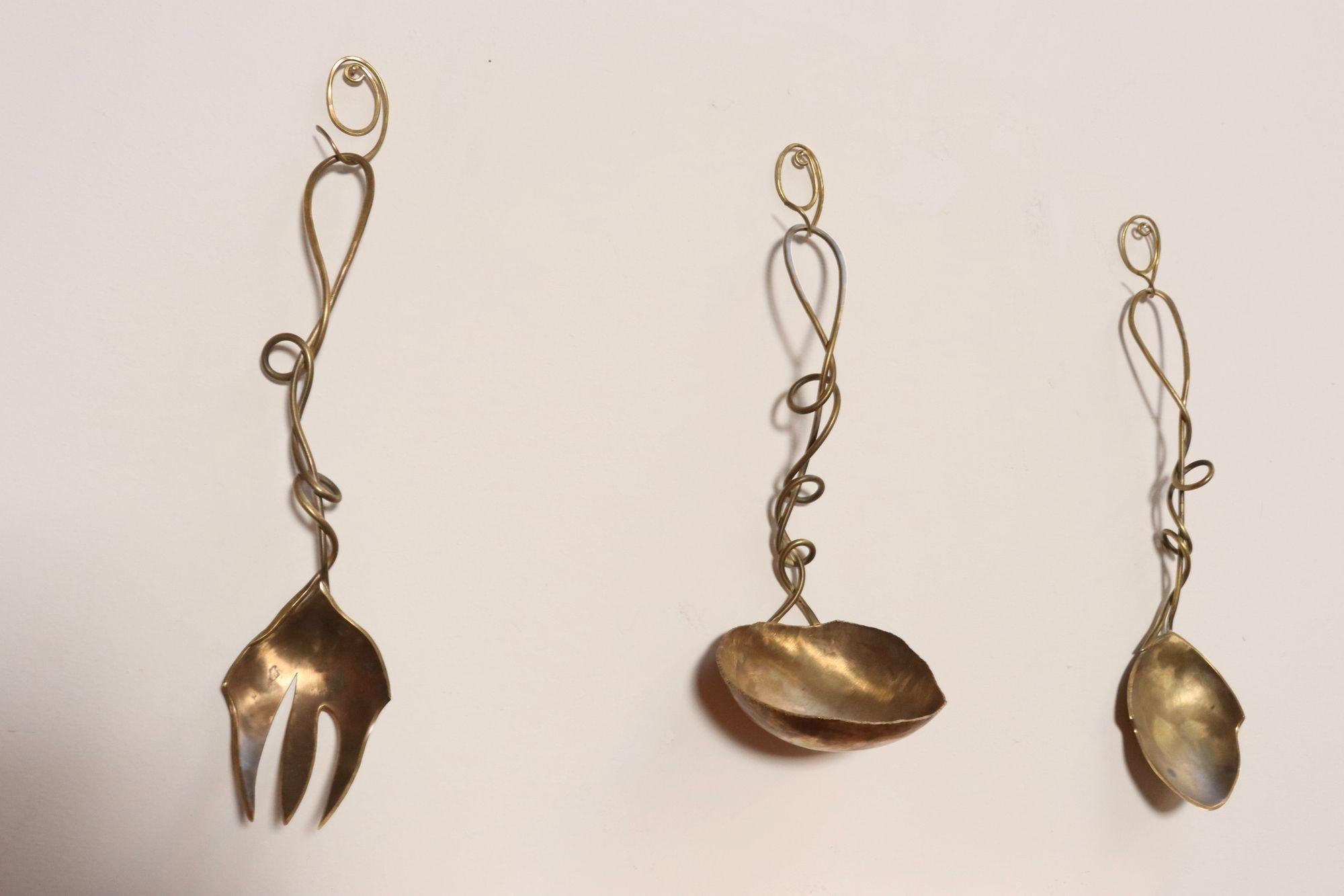 Brutalist-style brass serving pieces including ladle, spoon, and fork (ca. 1970s, likely Austrian).
Intriguing sinuous form handles with hand-forged and hammered details.
Intended for both decorative/display purposes, evidenced by the corresponding