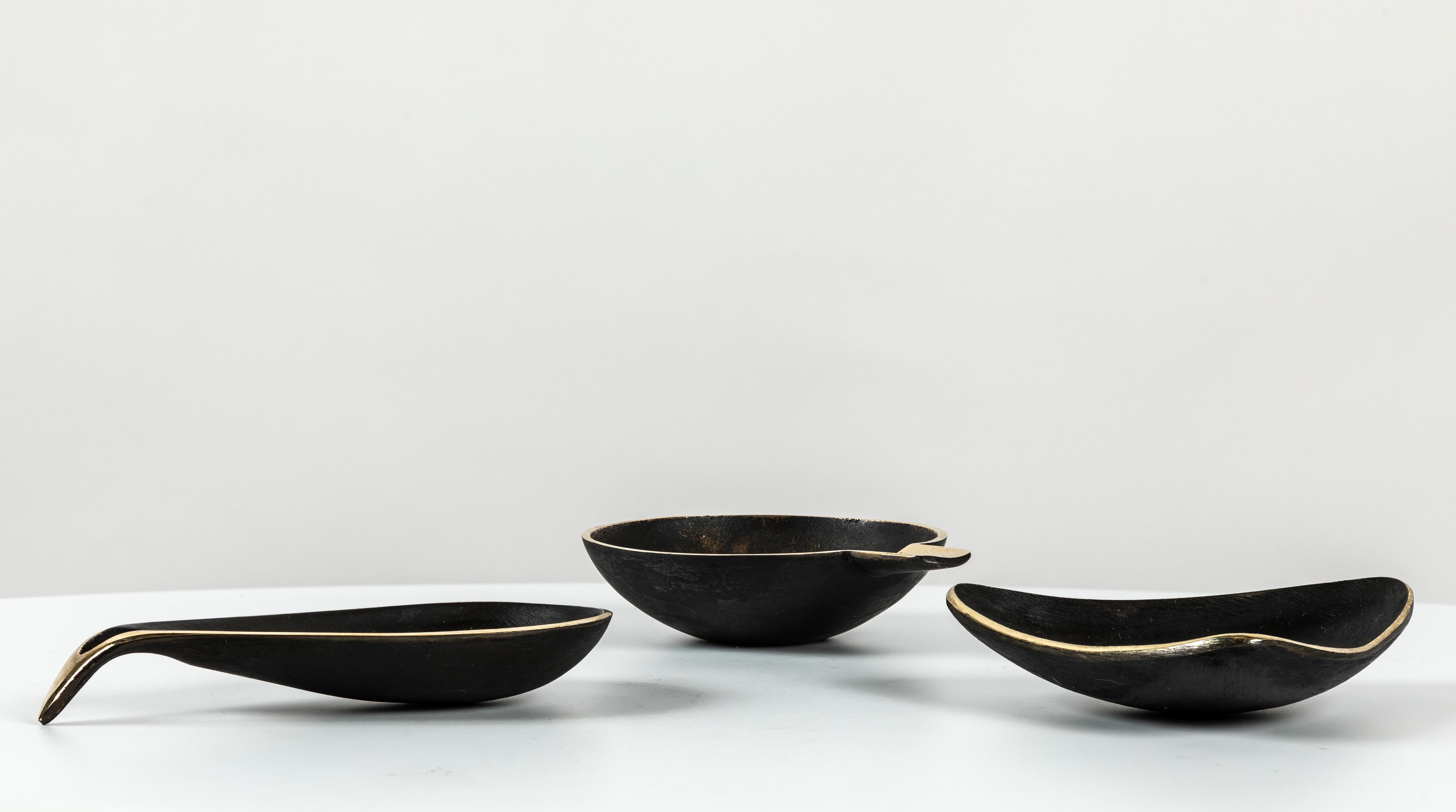 Ensemble de trois bols en laiton Carl Auböck. Comprend un exemplaire de chacun des modèles #3904, #3844 et #4082. Conçus dans les années 1950, ces bols viennois incroyablement raffinés et sculpturaux sont exécutés en laiton poli et sombrement