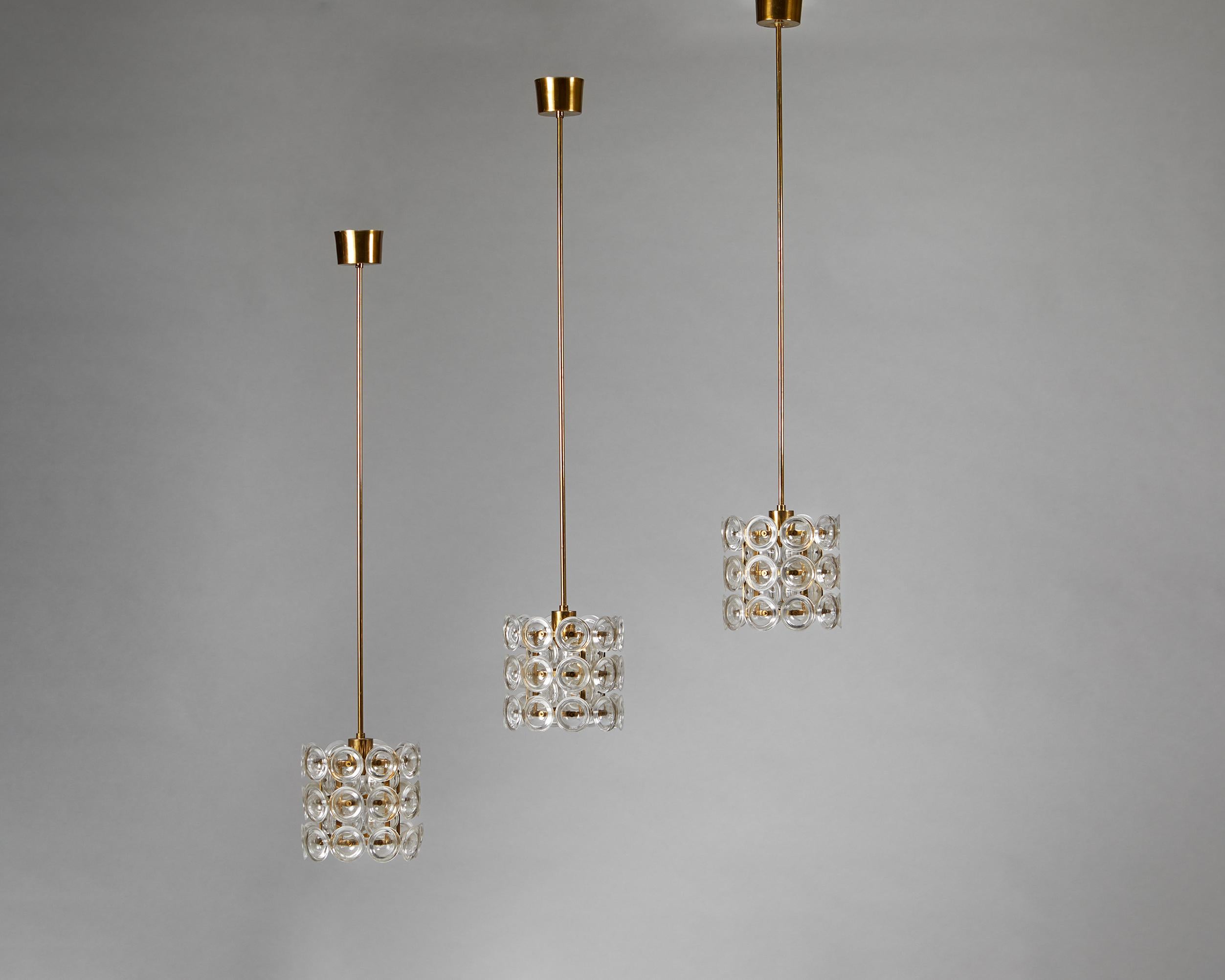 Set of three ceiling lamps designed by Carl Fagerlund for Orrefors,
Sweden, 1960's.
Brass and crystal.

These impressive ceiling lamps have two layers of circular glass cups cleverly aligned to protect the eyes from direct light. The inner and outer
