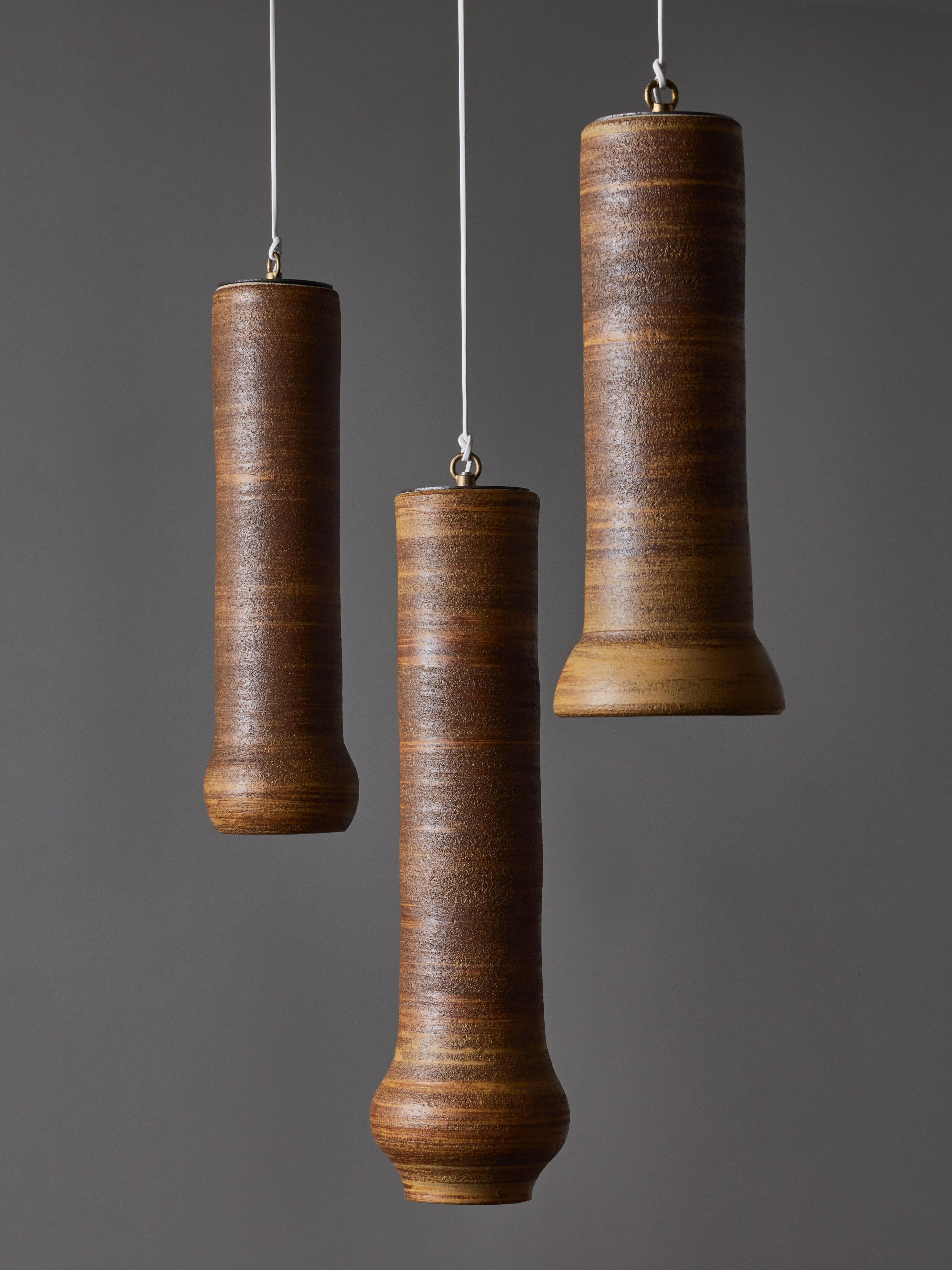 Set of three suspensions made of turned ceramic by the french artists Claude and Jean Bersoux.

Each suspension has a mat grainy finish in different shades of brown and beige on the outside and a glossy white finish inside helping reflecting the