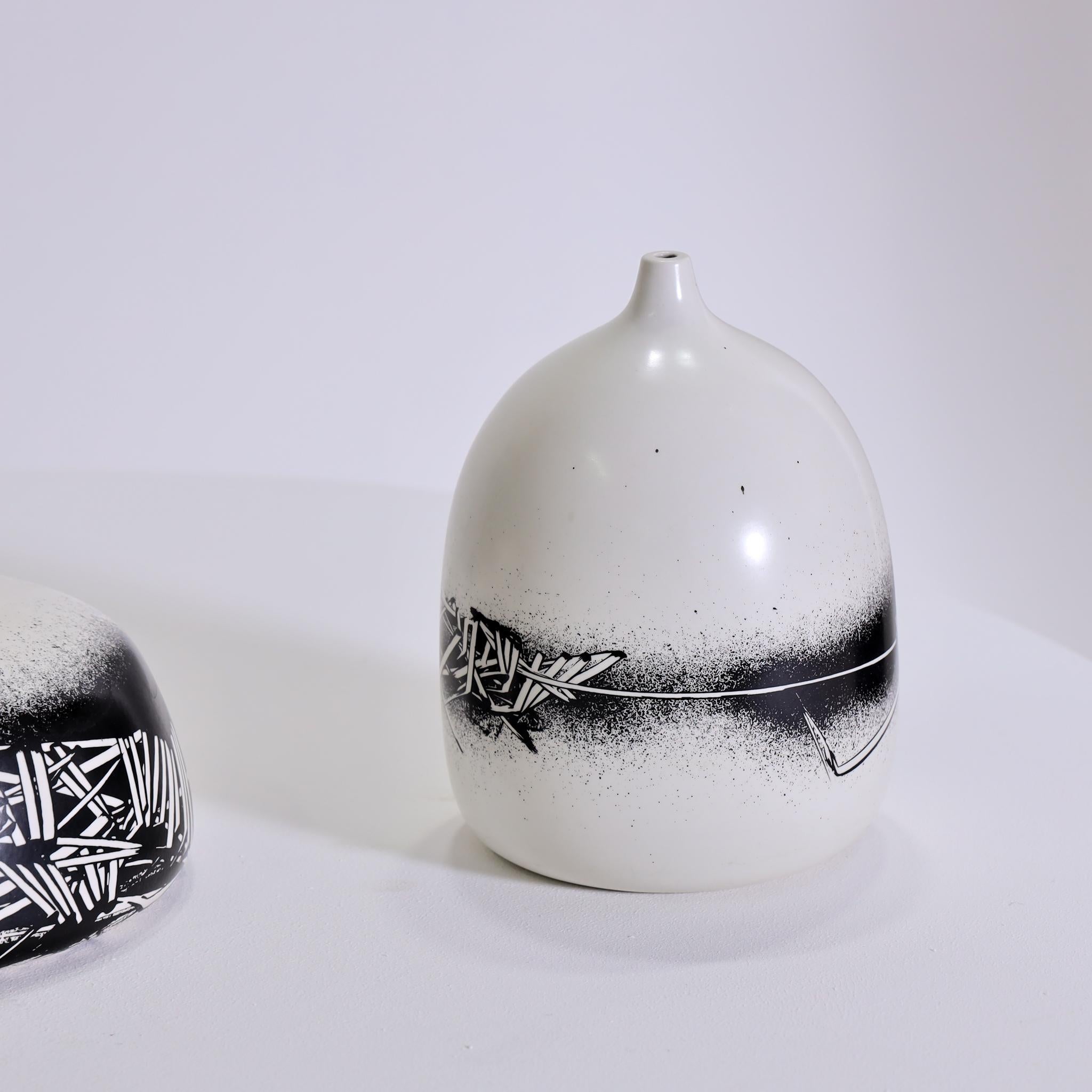Three ceramic vases designed by Emilio Scanavino for Motta, Italy, dating back to the 1970s. These off-white vases feature a distinctive black asymmetrical graffito pattern. Each vase is labeled at the bottom and numbered as part of a limited