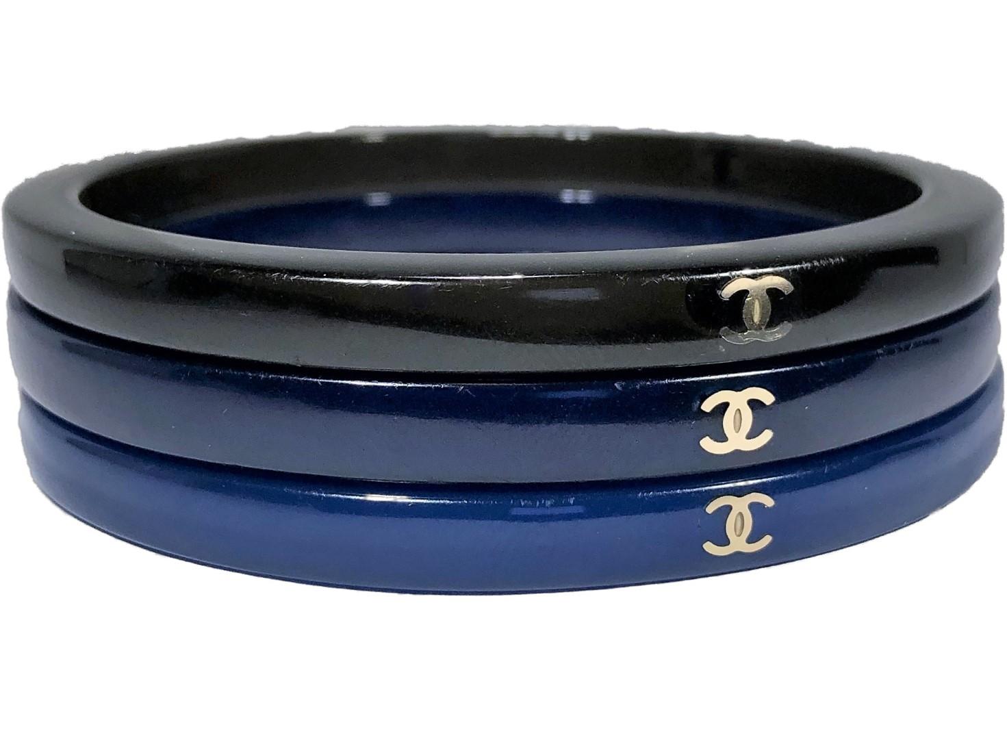 This set of three CHANEL bangles was released as part of the 2007 Cruise collection. All are imbedded with the CHANEL crossed C logo at three points around the circumference. Colors are medium blue, dark blue,  and black. Fits medium to large wrist